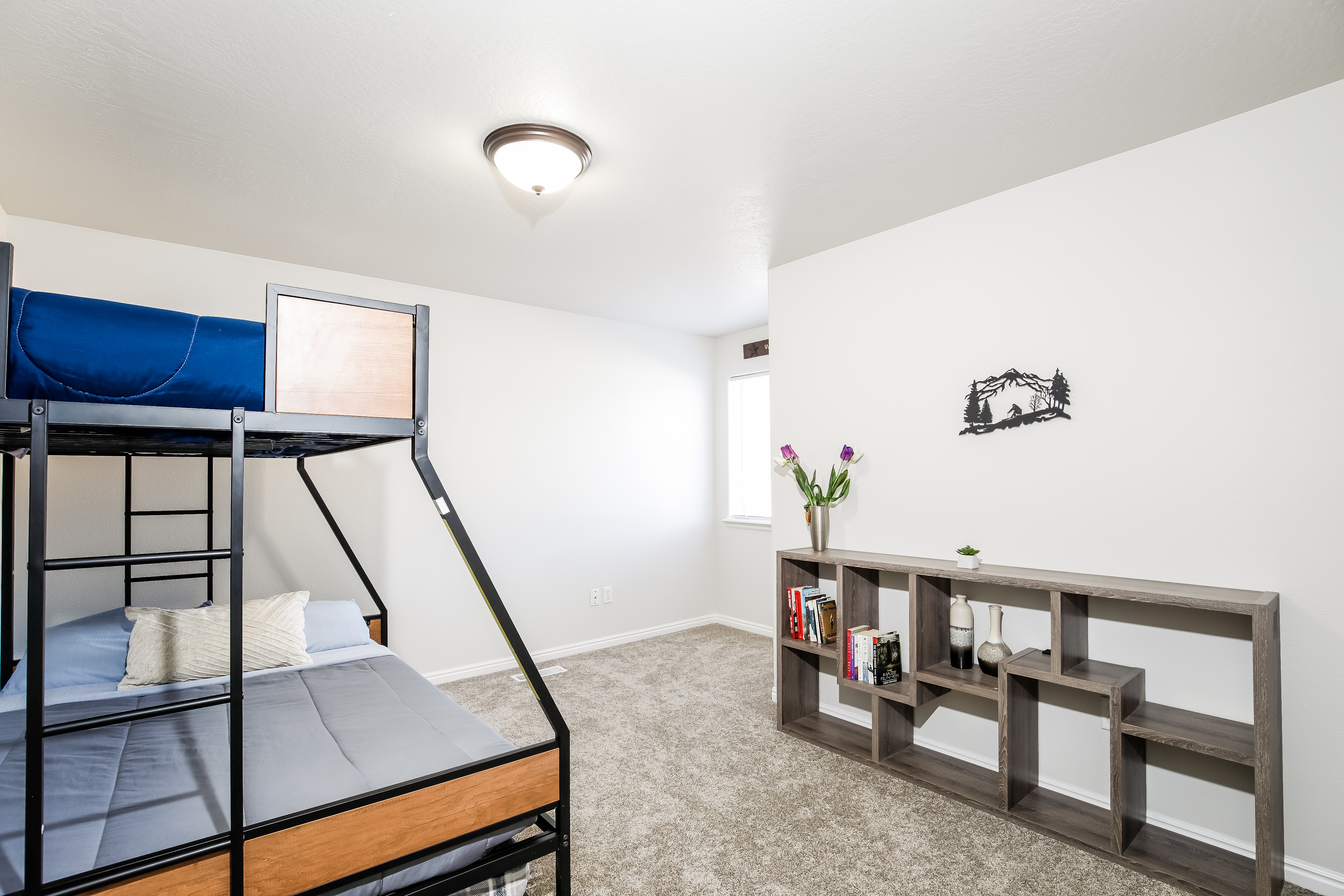 Bright bunk room with twin-over-full bed, shelving, and natural light