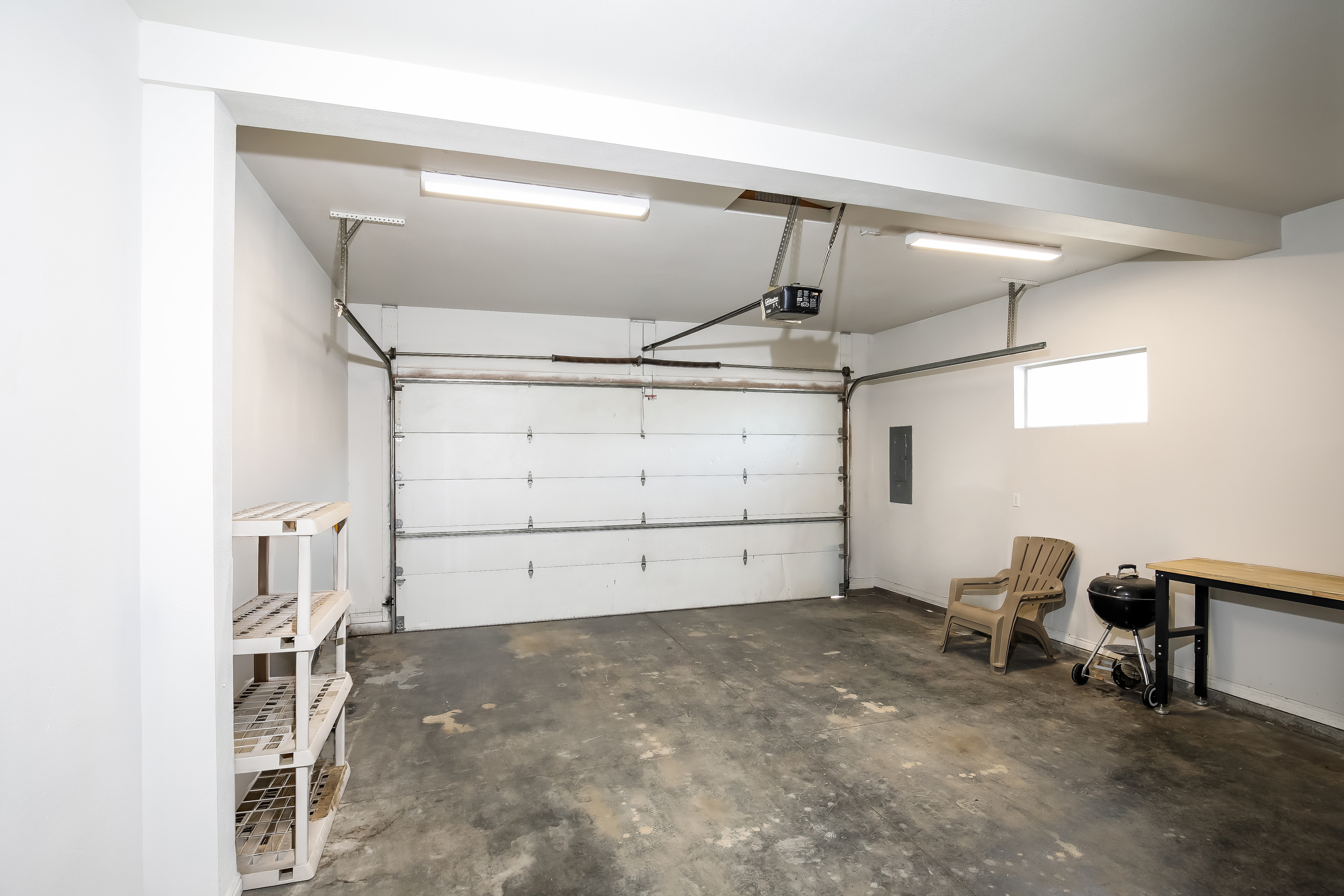 Bright two-car garage with opener, shelving and workbench space