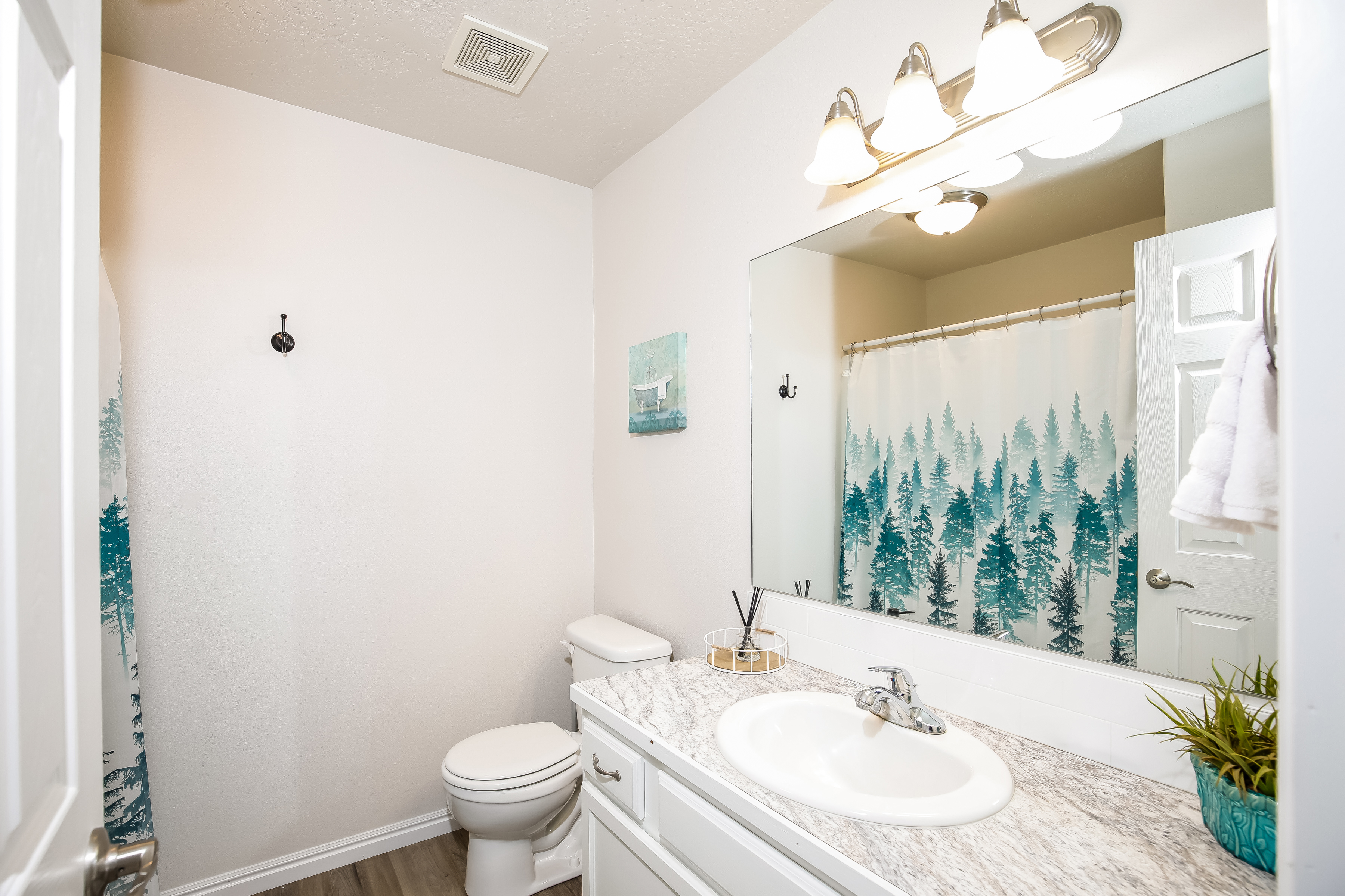 Bright, spotless bath with large mirror and stylish forest accents