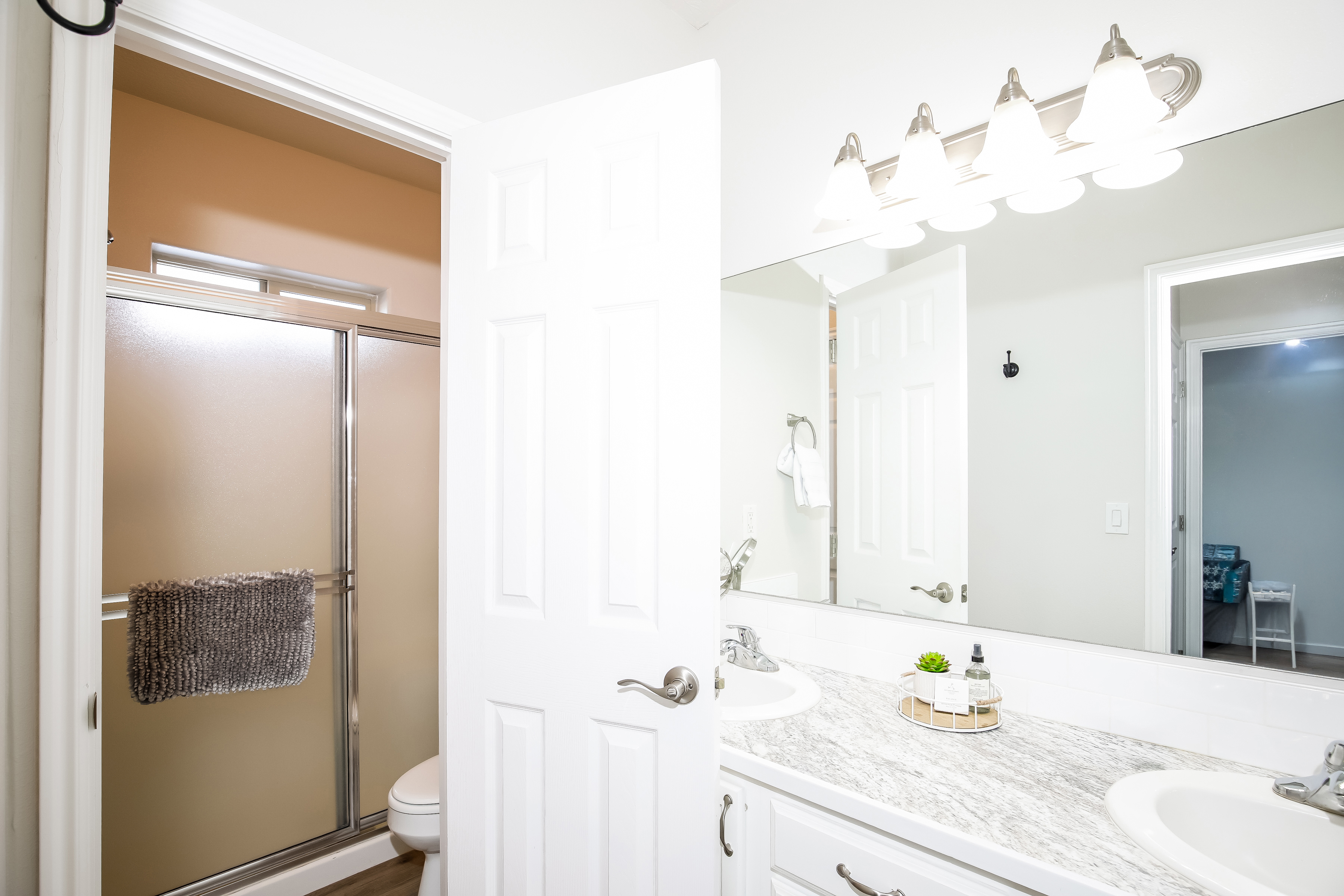Bright bath with double vanity, glass shower, and ample lighting