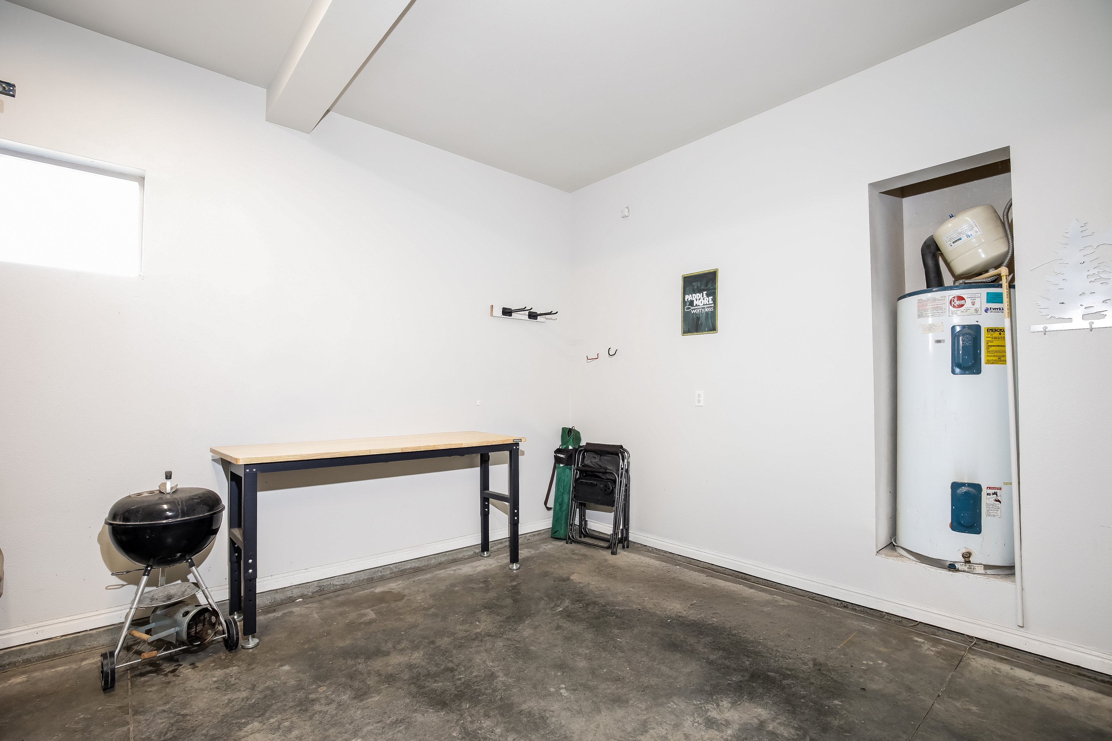 Bright garage with workbench, charcoal grill, and gear storage.