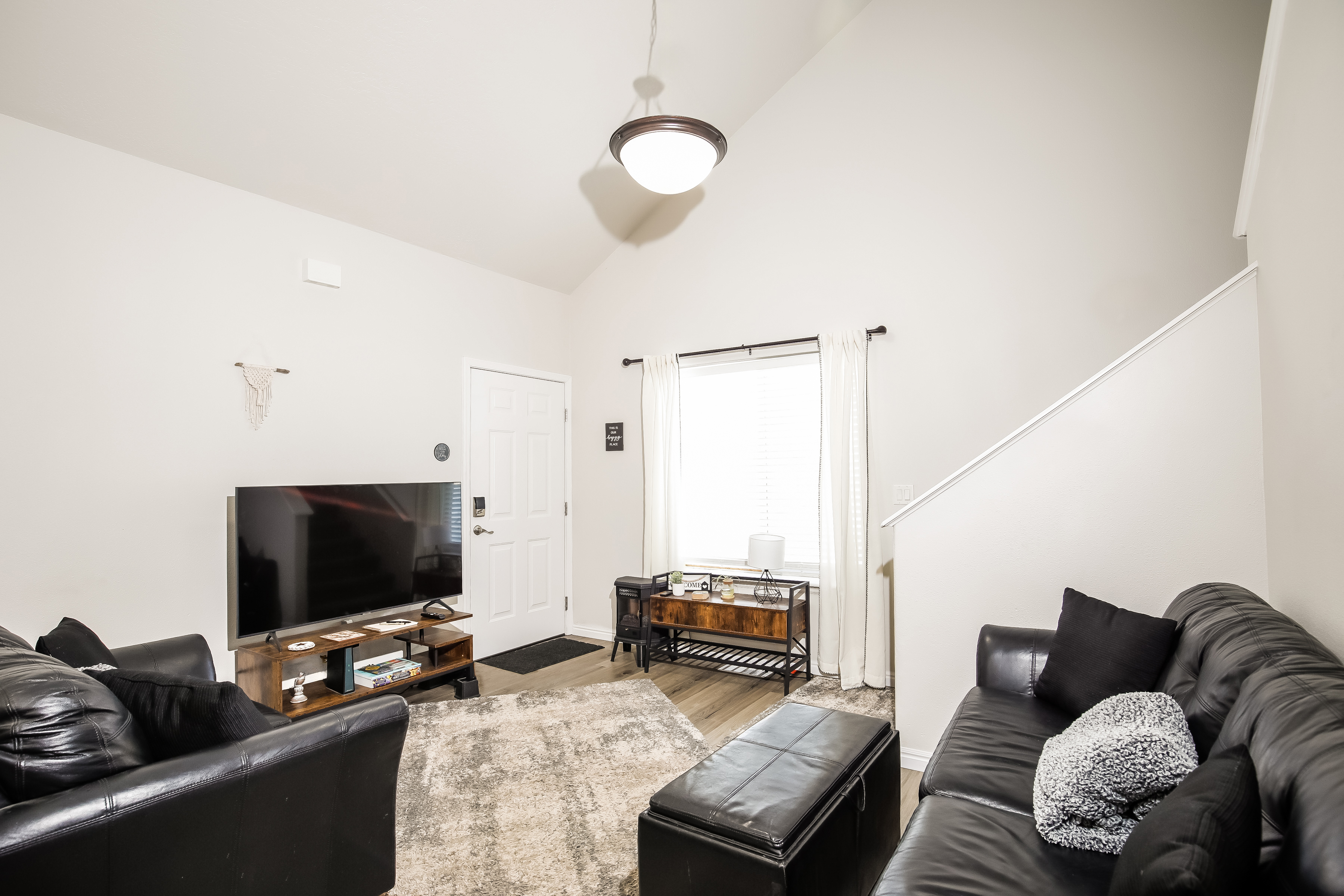Bright living room with vaulted ceilings, leather sofas & smart TV