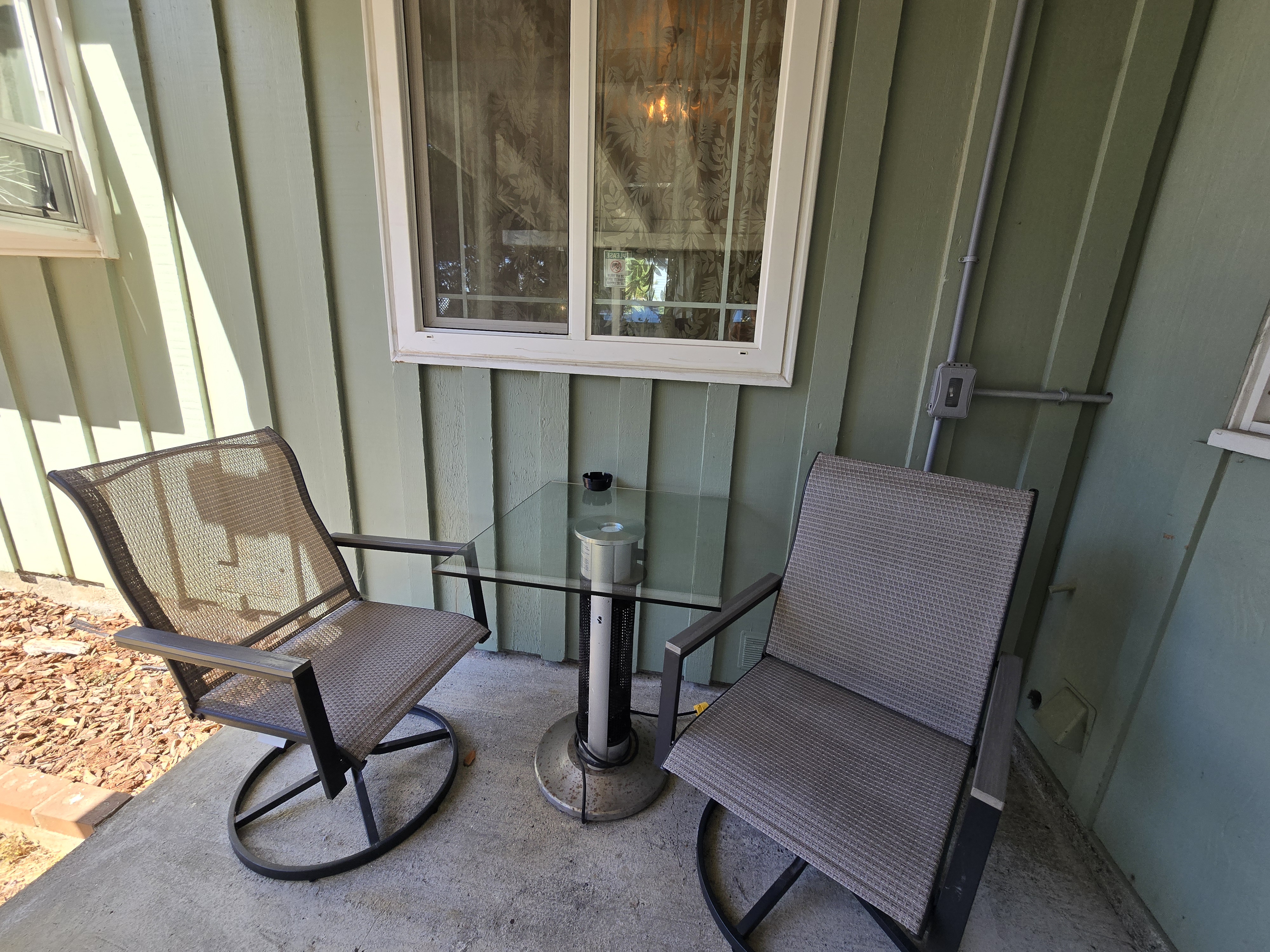 Cozy covered patio nook with swivel chairs and a glass bistro table