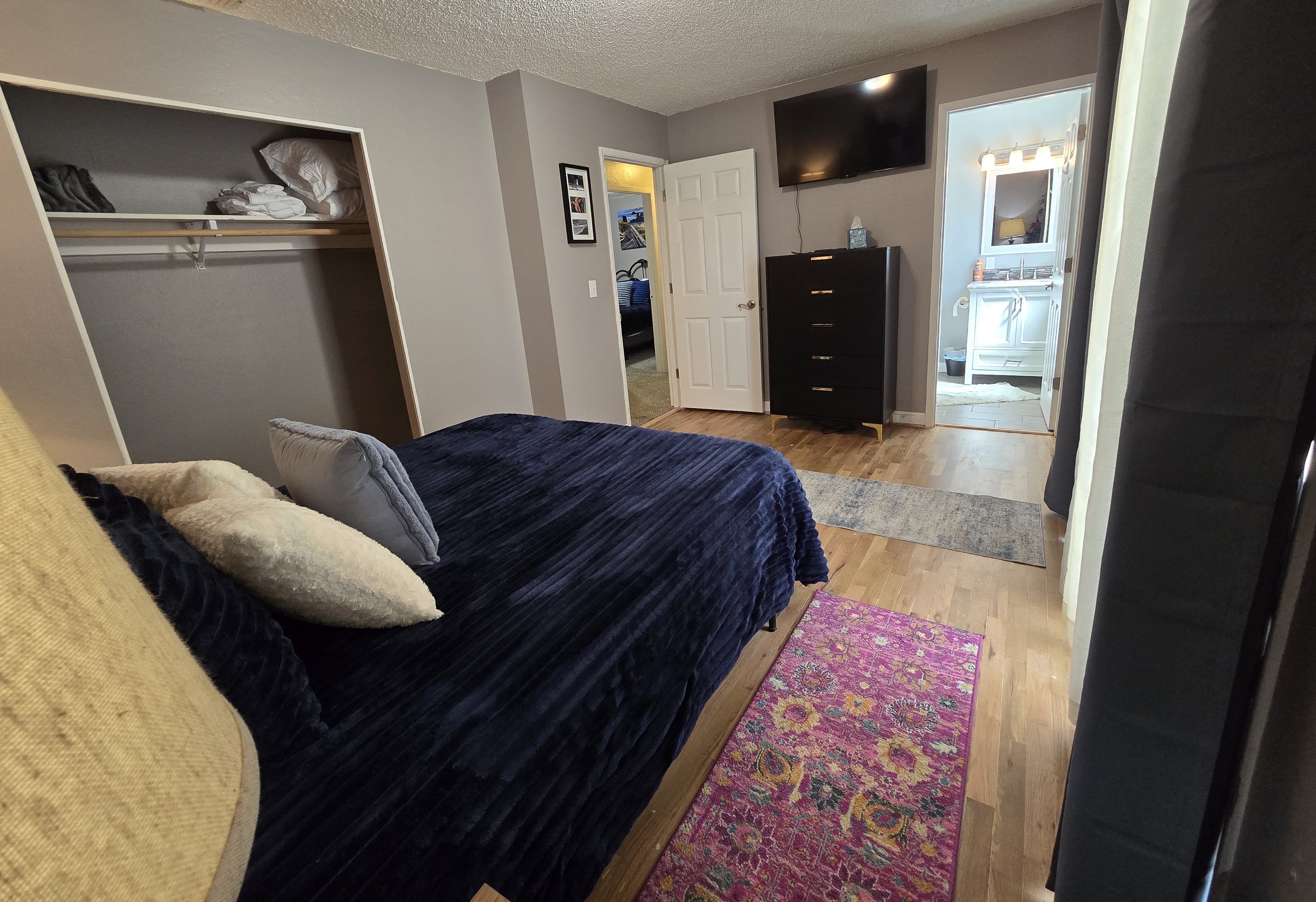 Cozy bedroom with TV, dresser, closet, and en suite bath access