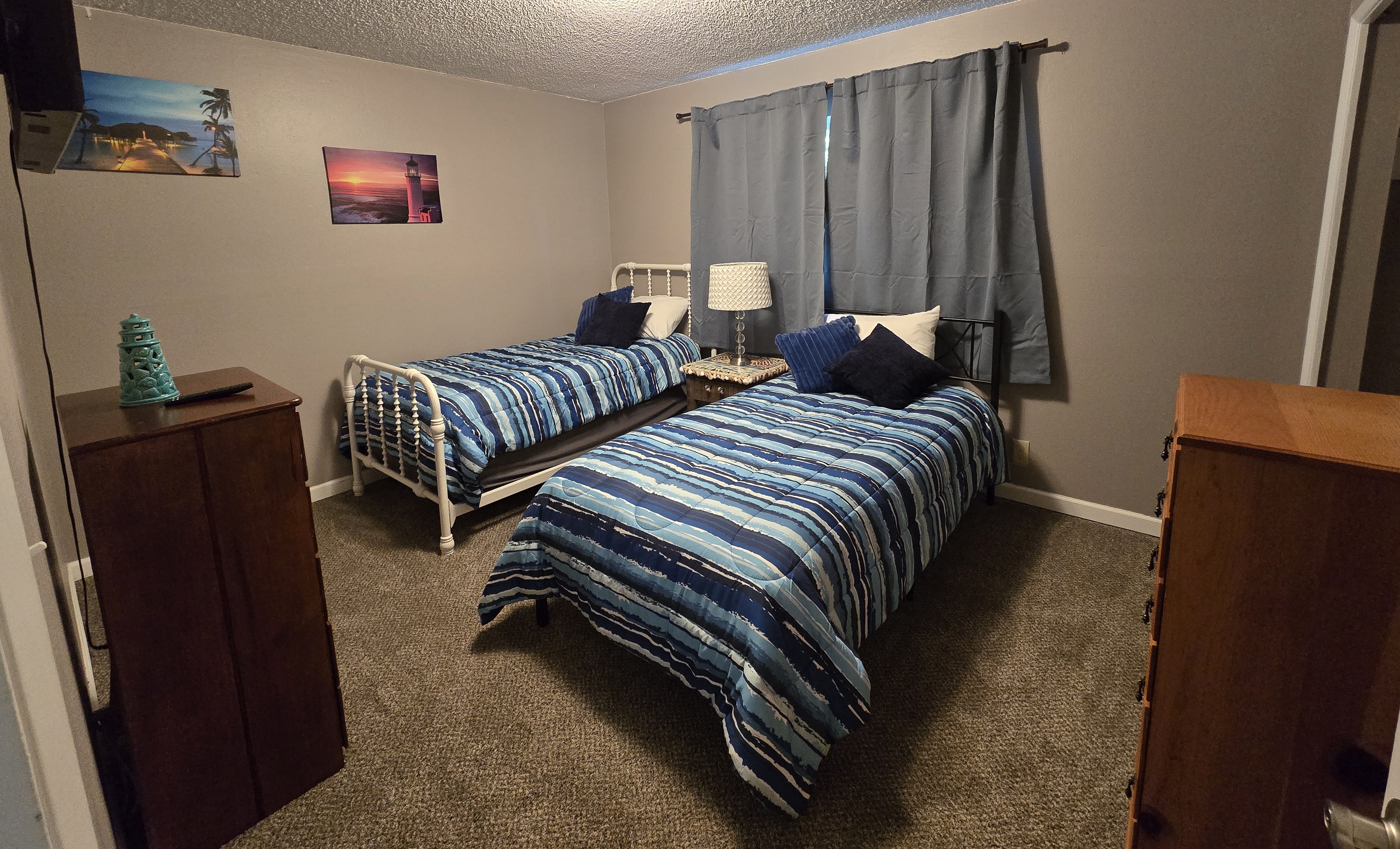 Cozy twin bedroom with soft carpet, storage, and stylish blue accents