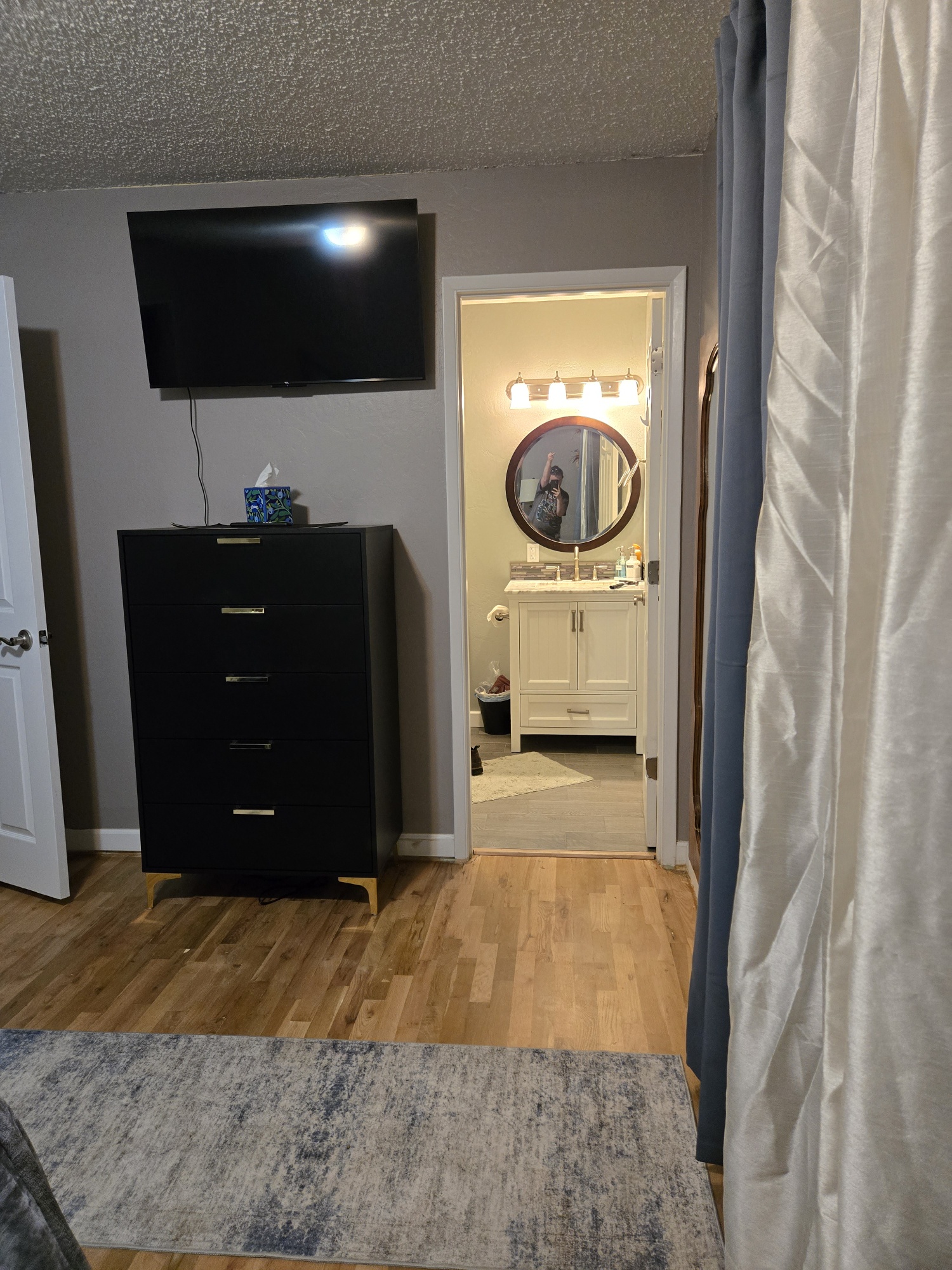 Bedroom with TV, dresser, and easy access to a bright private bath