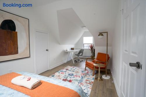 Bright attic bedroom with workspace, floral rug, and cozy lounge chair