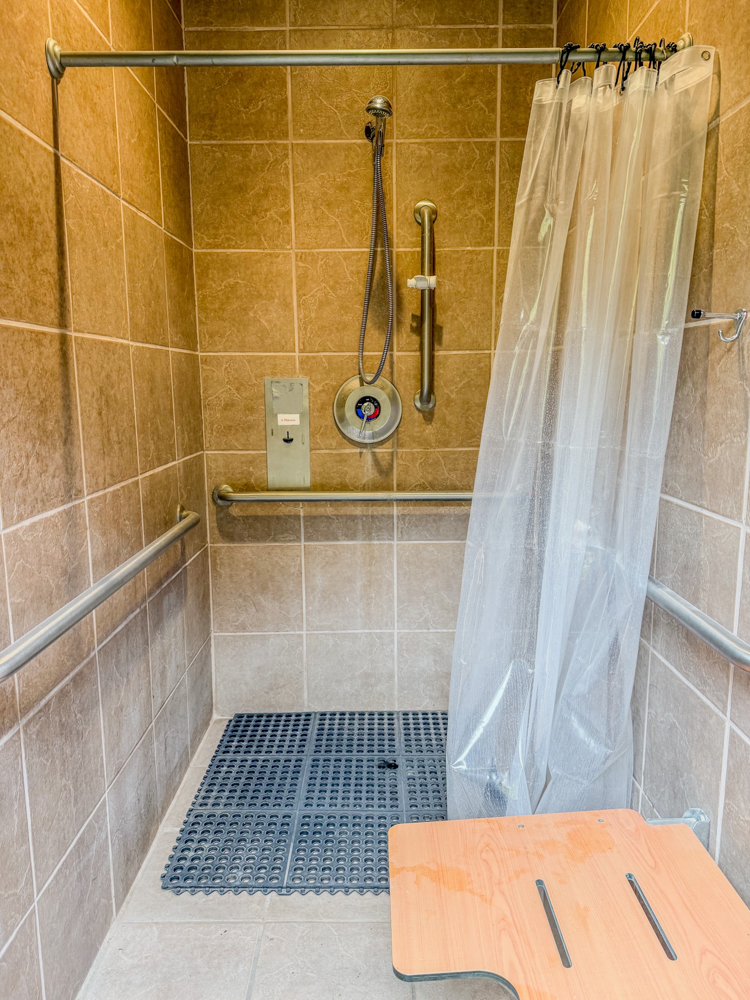Spacious accessible roll-in shower with grab bars and foldable bench