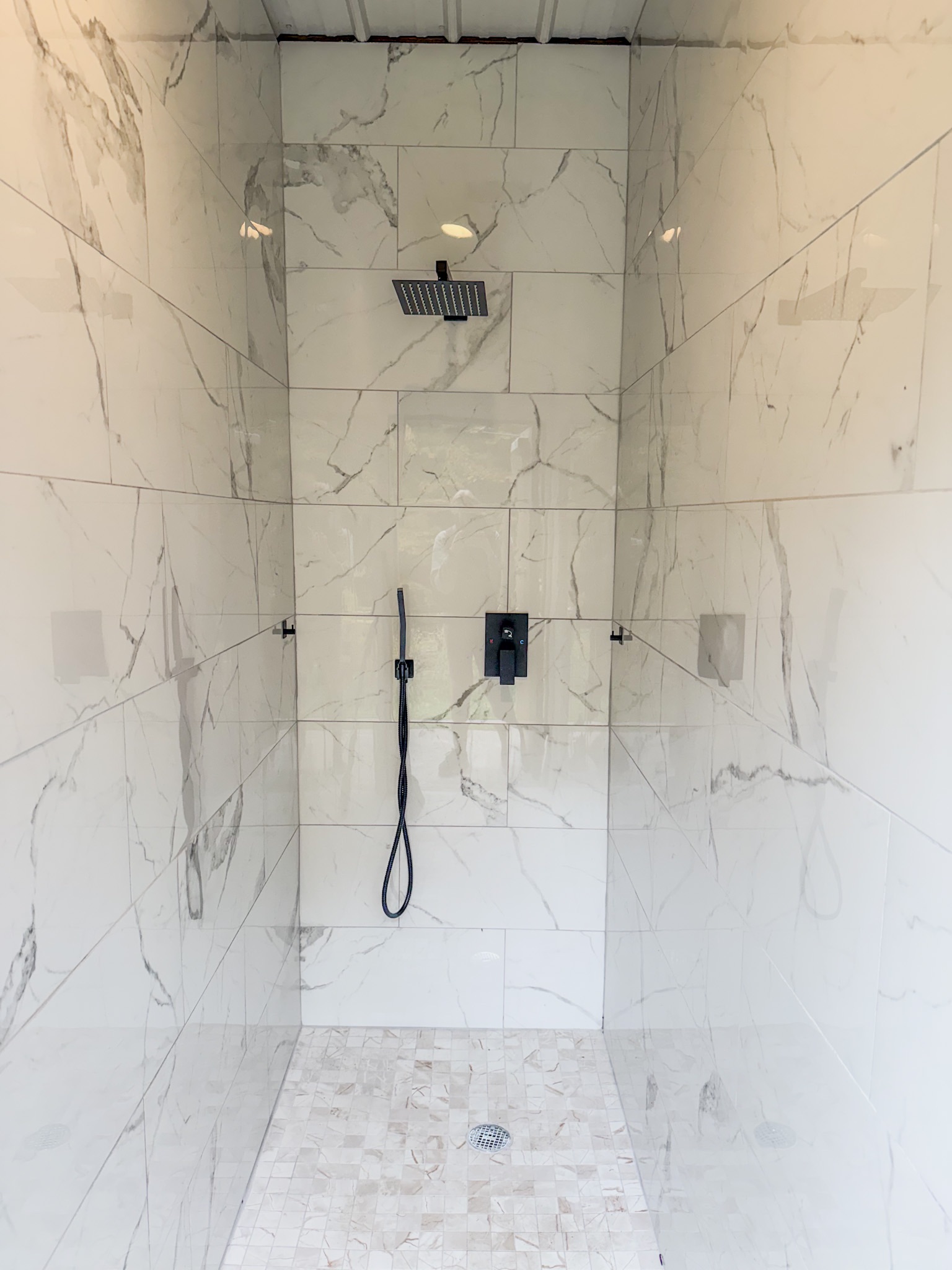 Spa-style walk-in shower with marble tile and modern black fixtures
