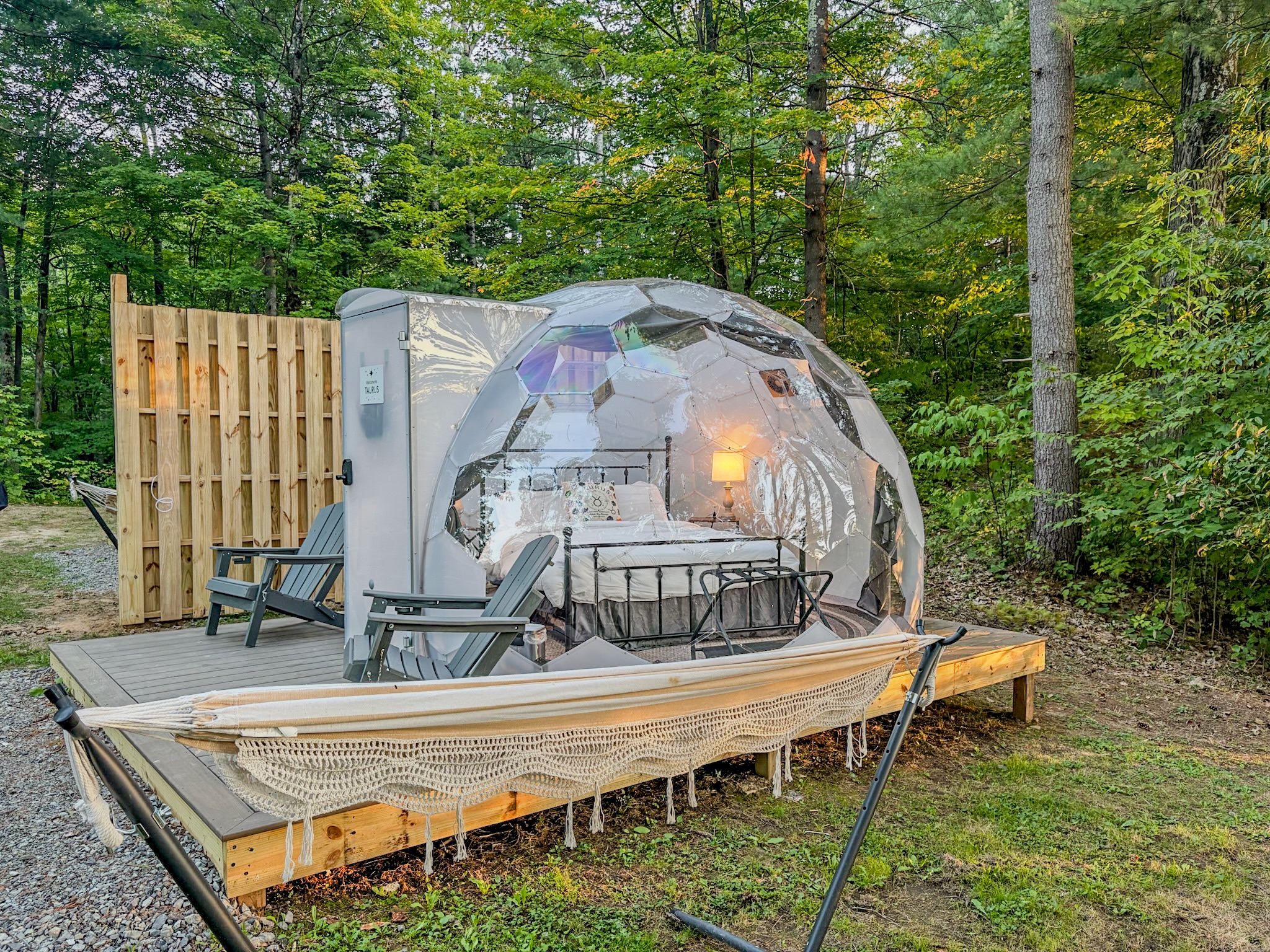Unique forest glamping dome with cozy bed, deck chairs, and hammock