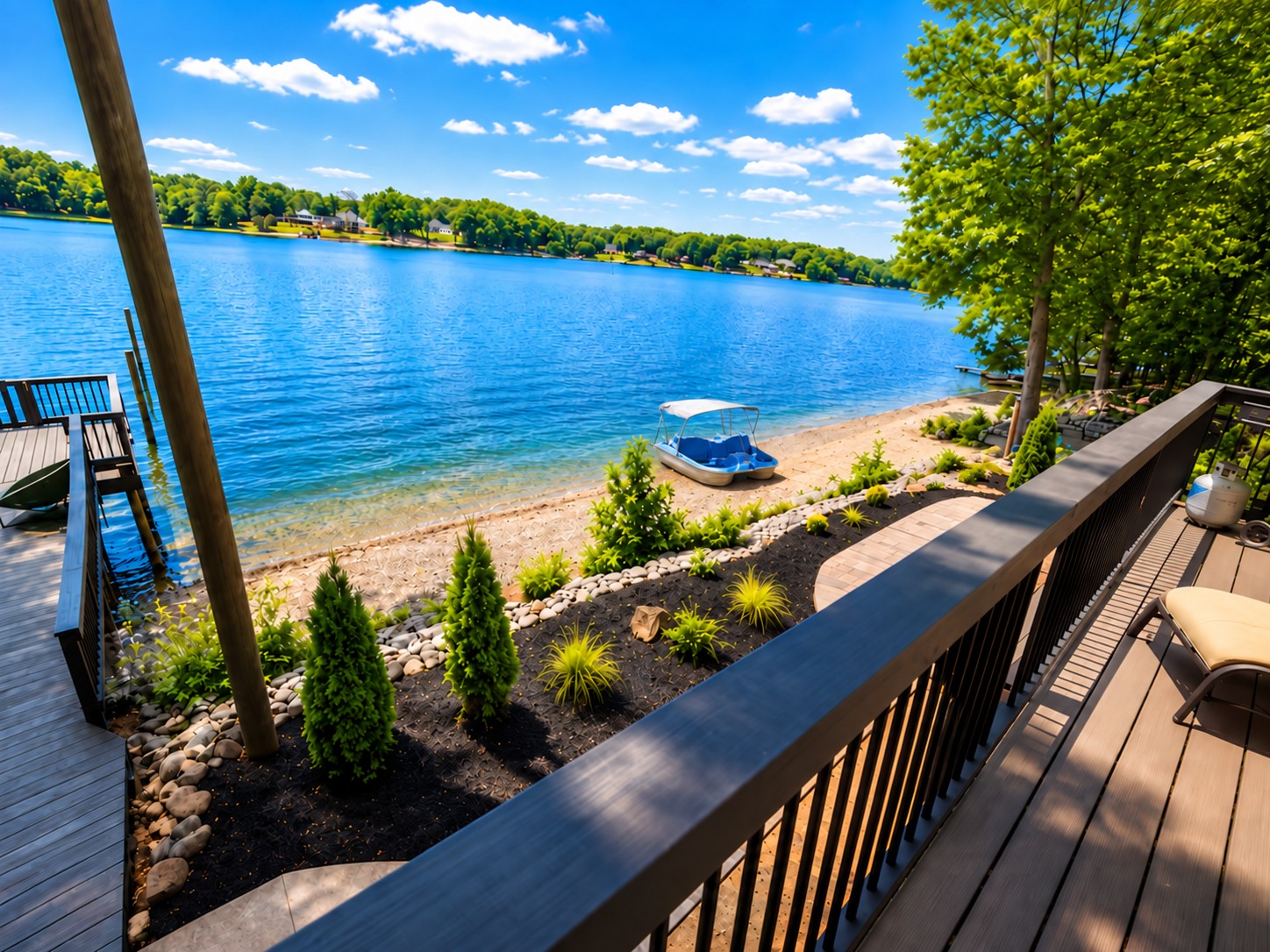 Sunny lakefront deck with sandy beach, dock, and stunning water views