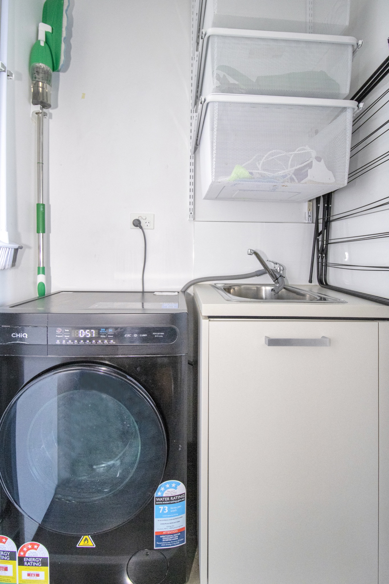 Convenient laundry nook with washer, utility sink, and handy storage
