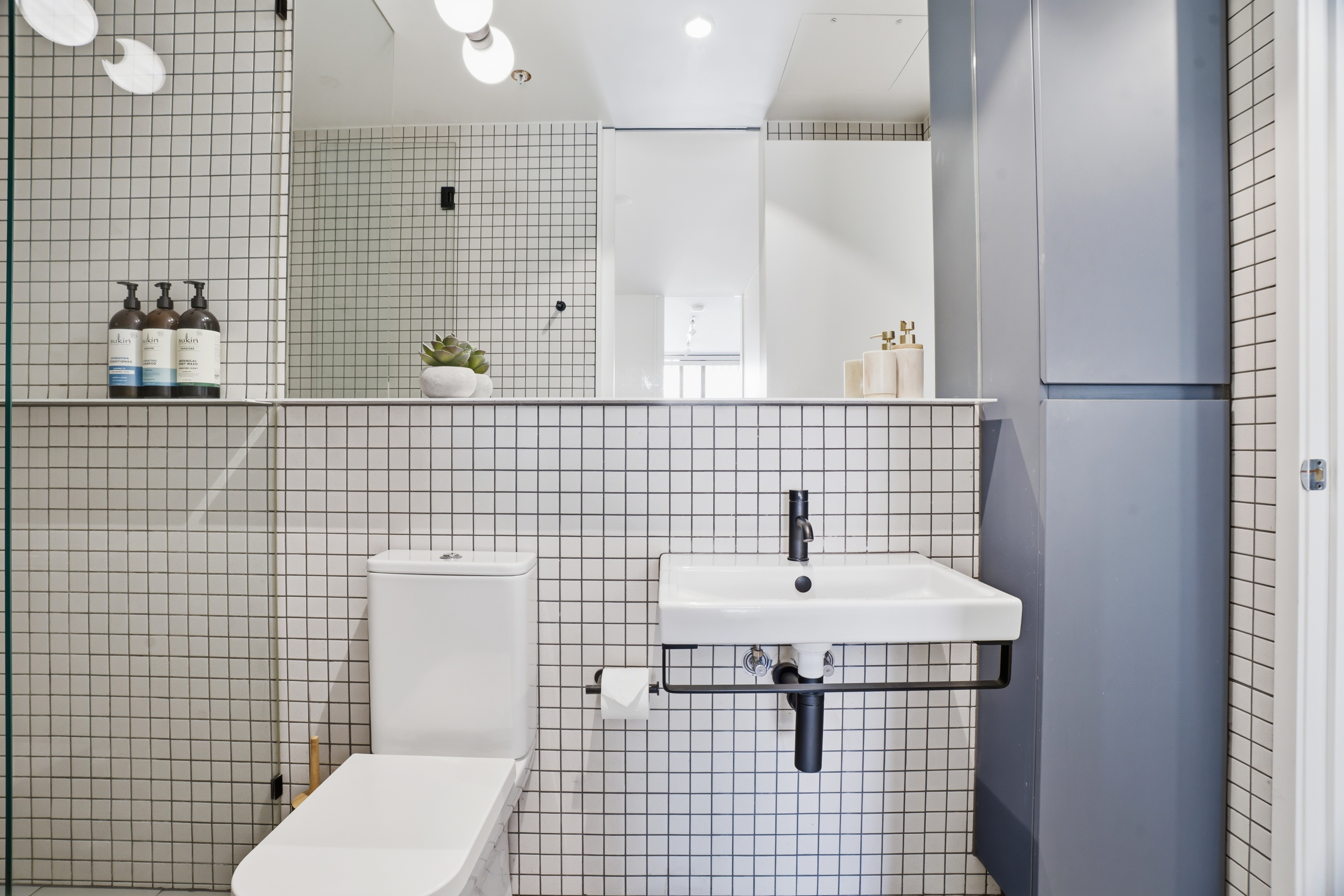 Bright modern bathroom with sleek tile, mirror, and built-in storage