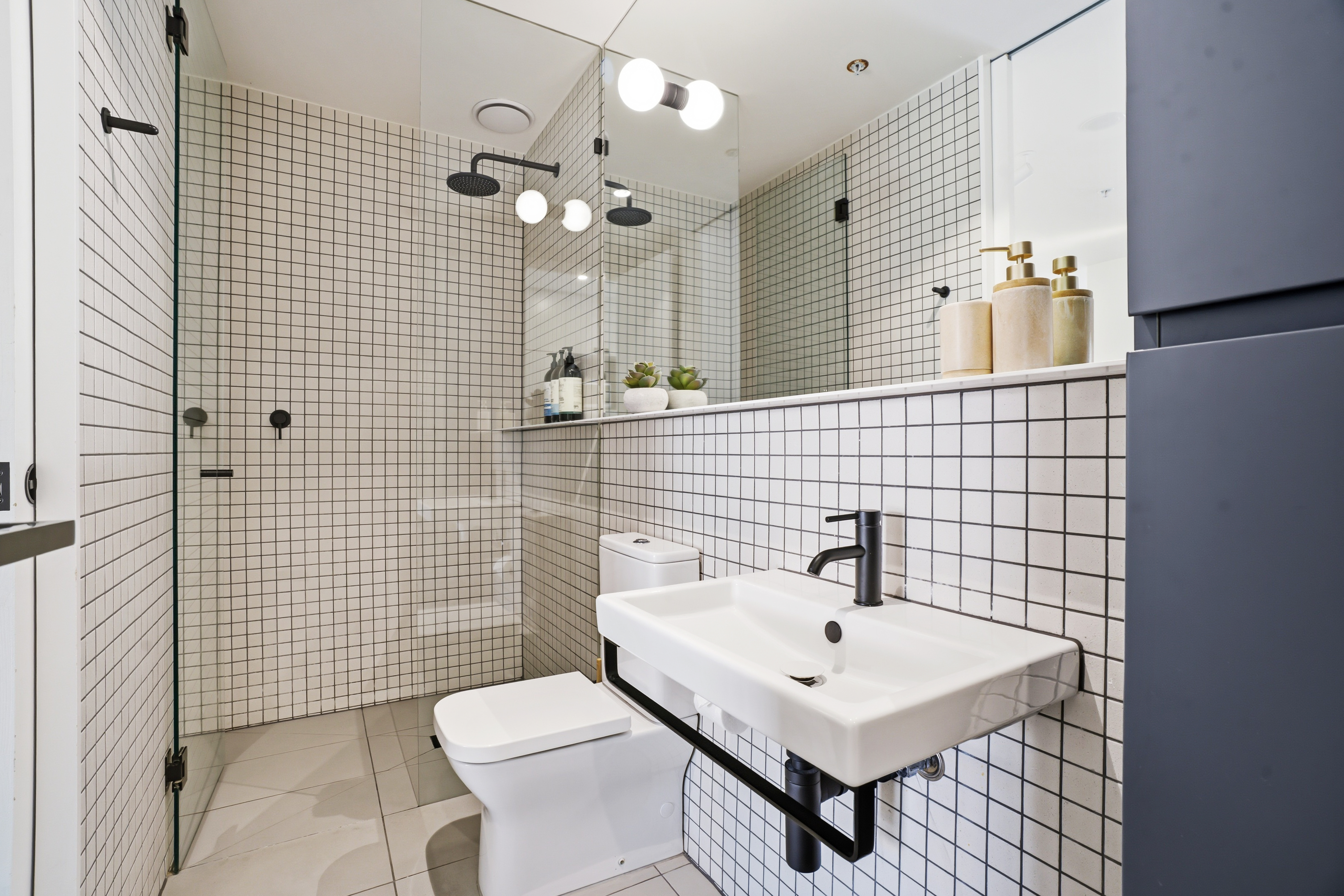 Modern tiled bathroom with walk-in glass shower and sleek black fixtures