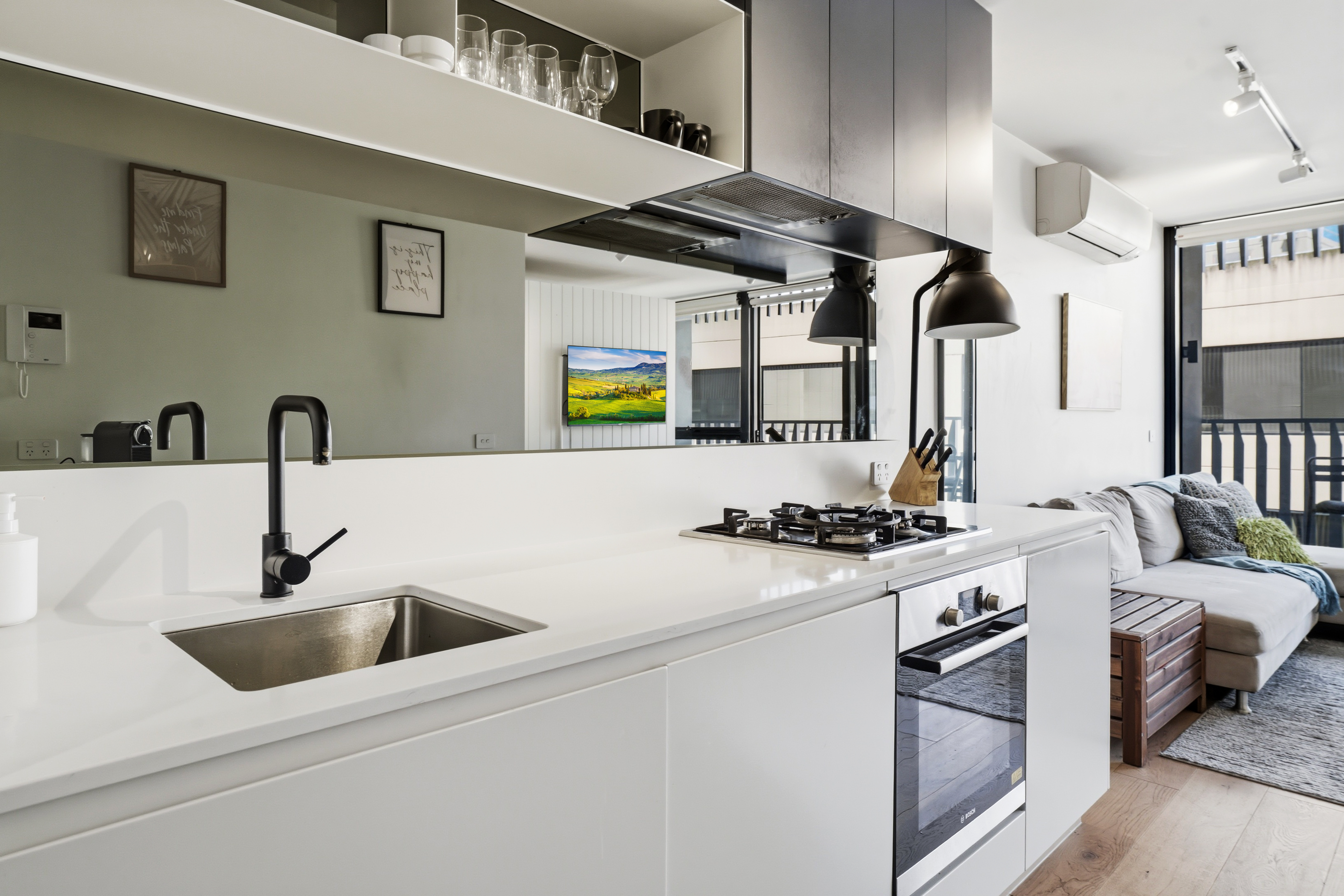 Modern open-plan kitchen and lounge with sleek finishes and balcony light