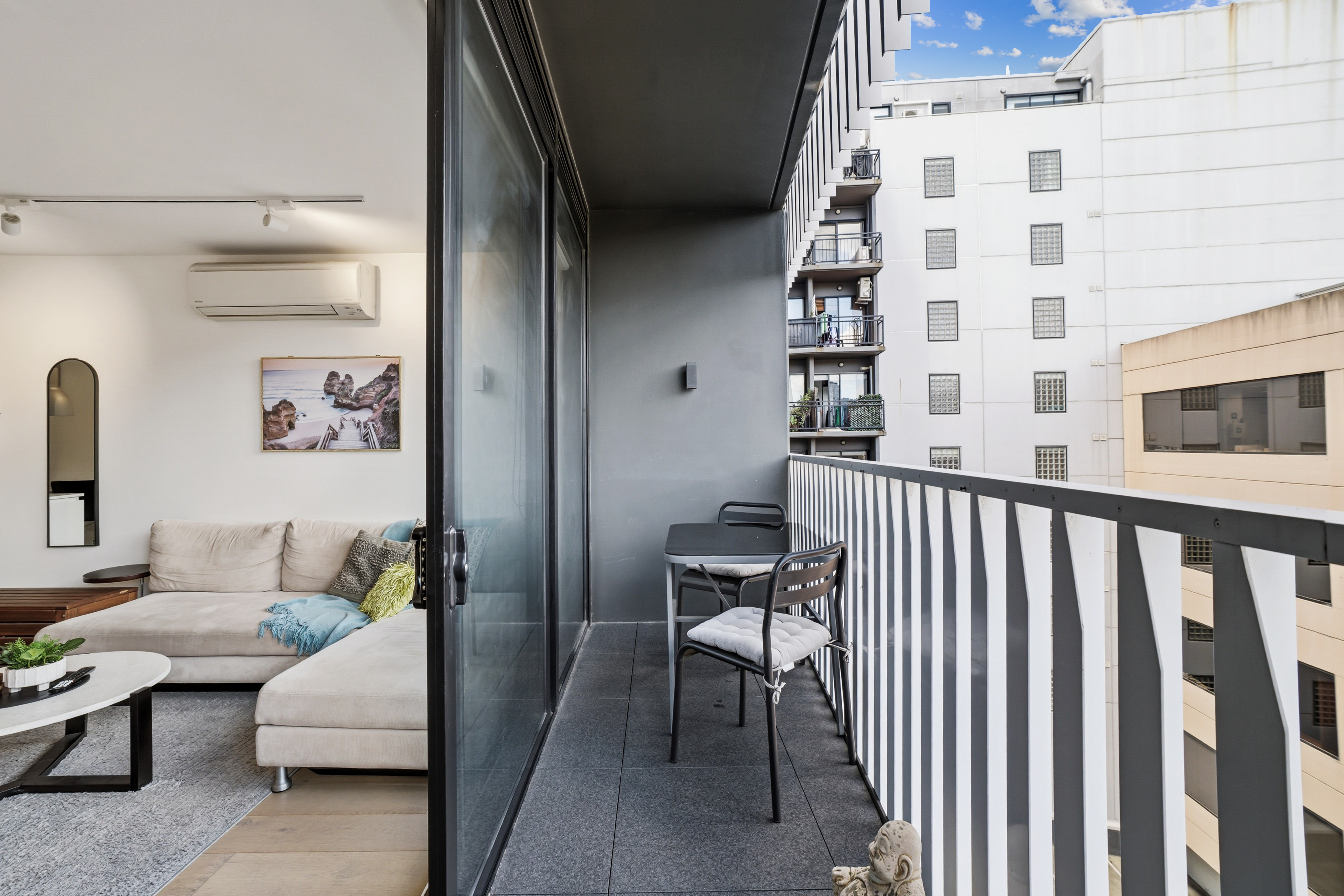 Private city-view balcony with bistro seating and bright modern living room