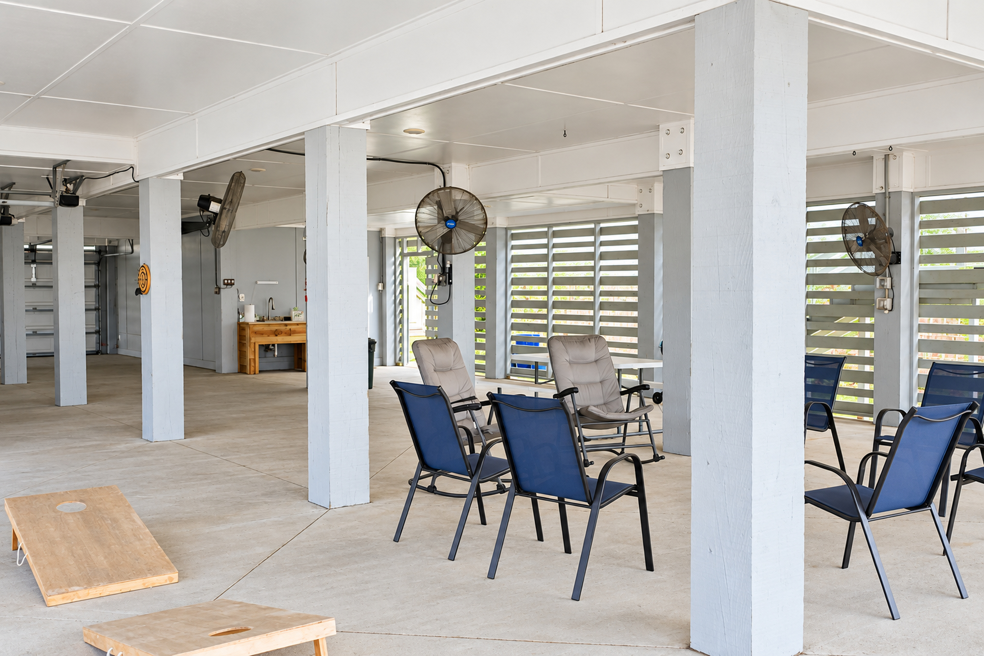 Spacious covered patio with lounge seating, fans, and cornhole fun