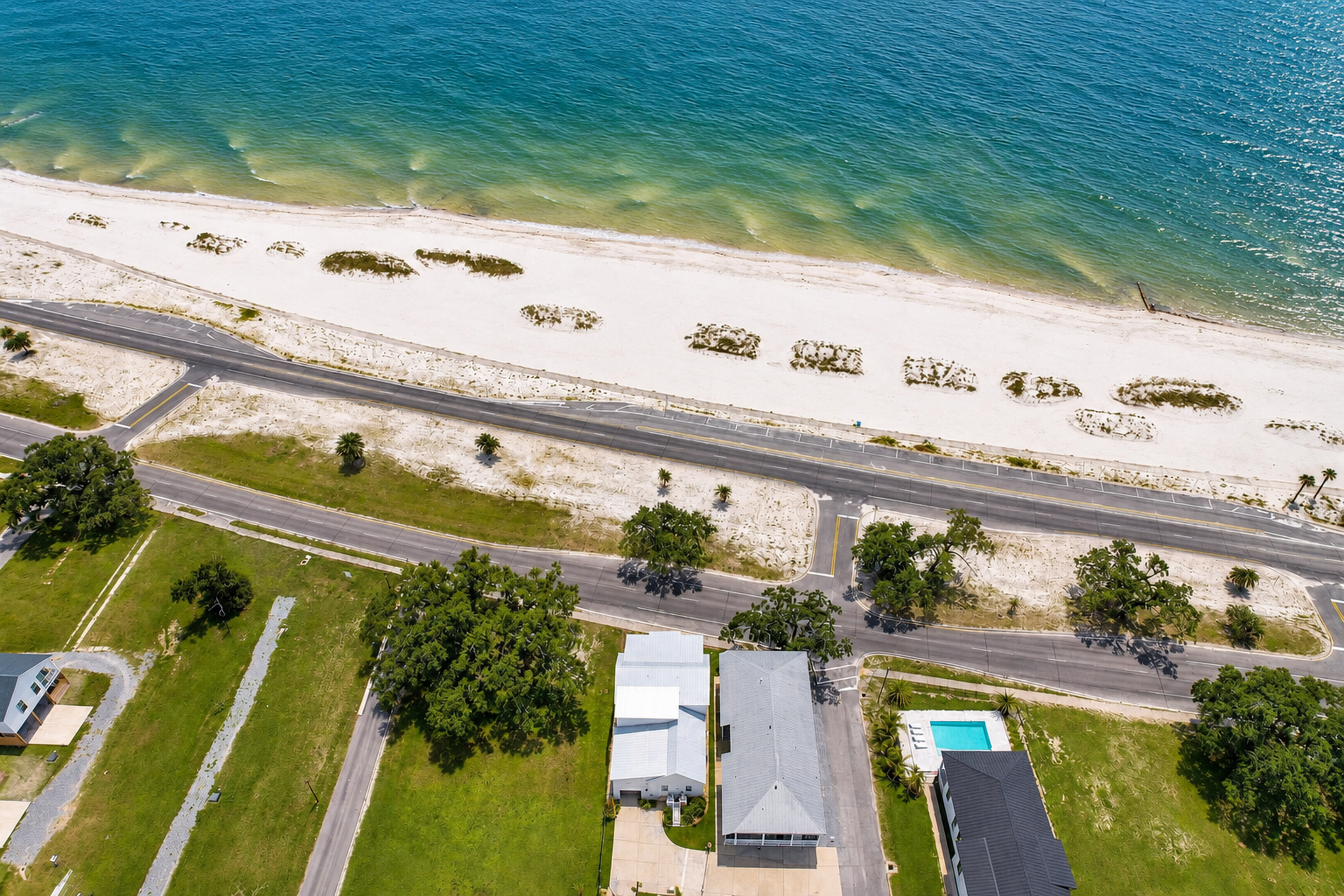 Aerial view of beachside home with pool steps from the sand
