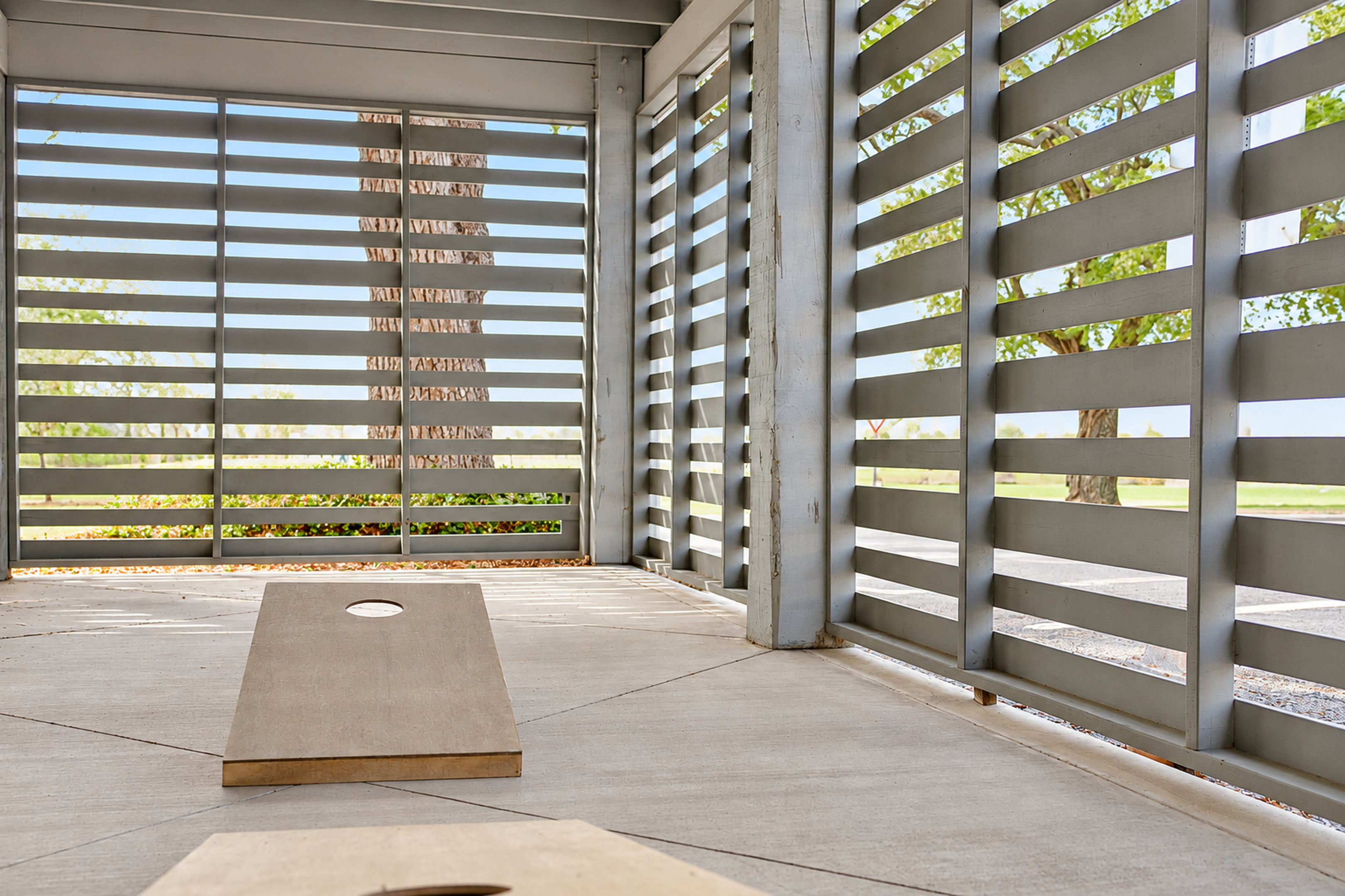 Shaded outdoor patio with cornhole and modern privacy screens