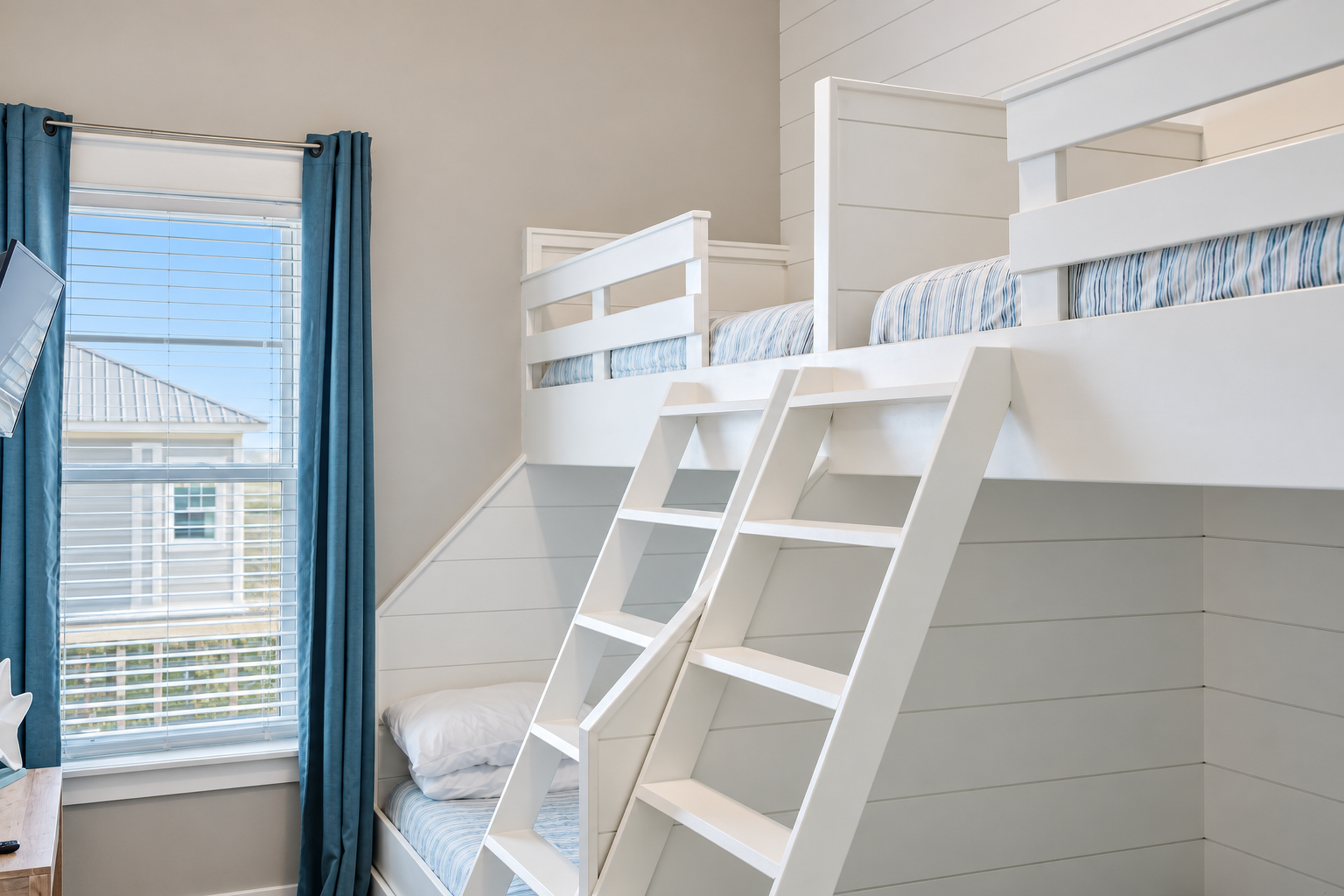 Bright coastal bunk room with built-in beds and extra sleeping nook