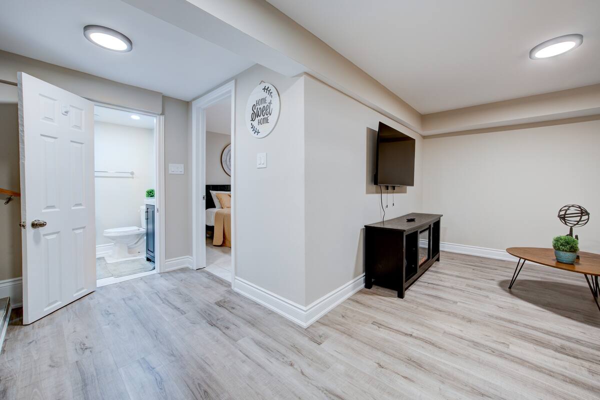 Bright basement suite with TV lounge, modern bath, and cozy bedroom.