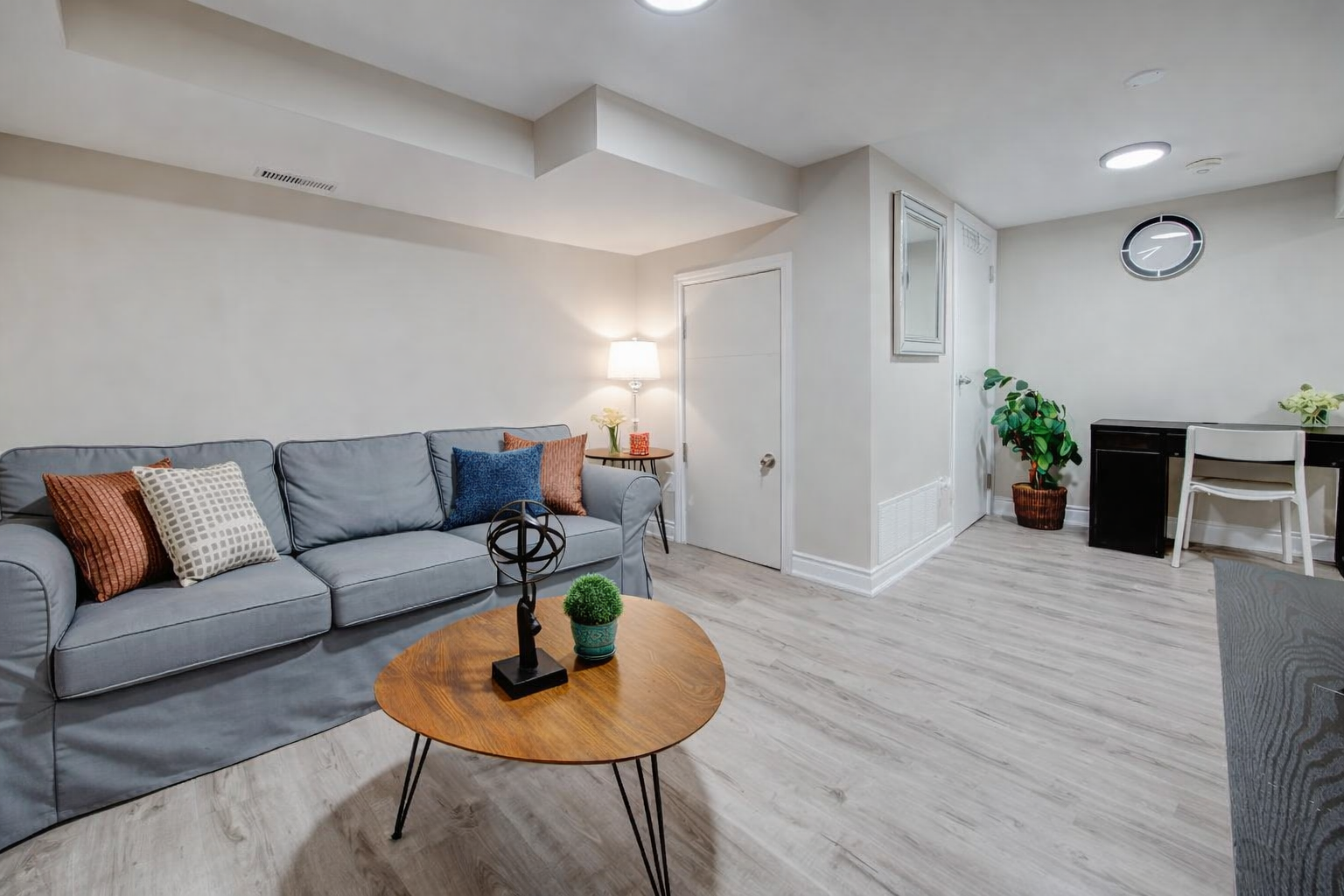 Bright lounge with comfy sofa, workspace, and sleek wood floors