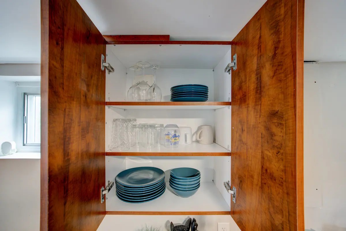 Well-stocked cabinet with matching dishes, bowls, glasses, and mugs