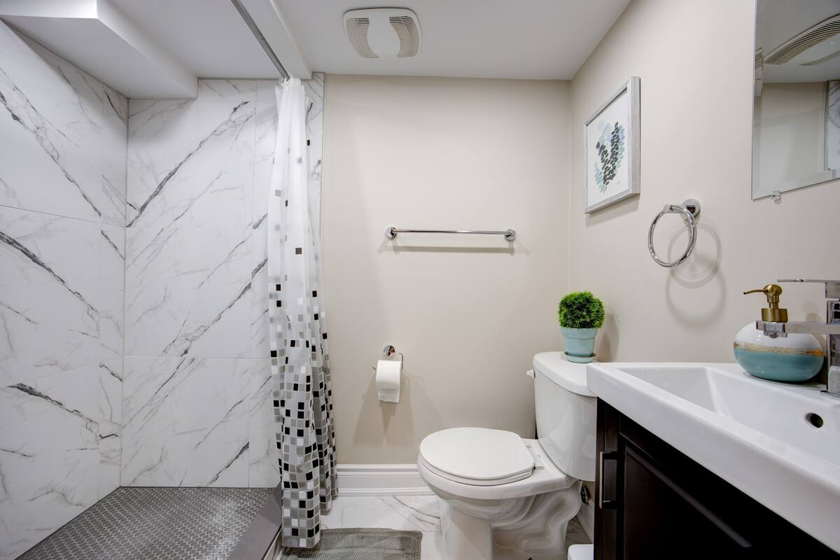 Bright modern bath with marble-tile shower, sleek vanity, and fresh decor
