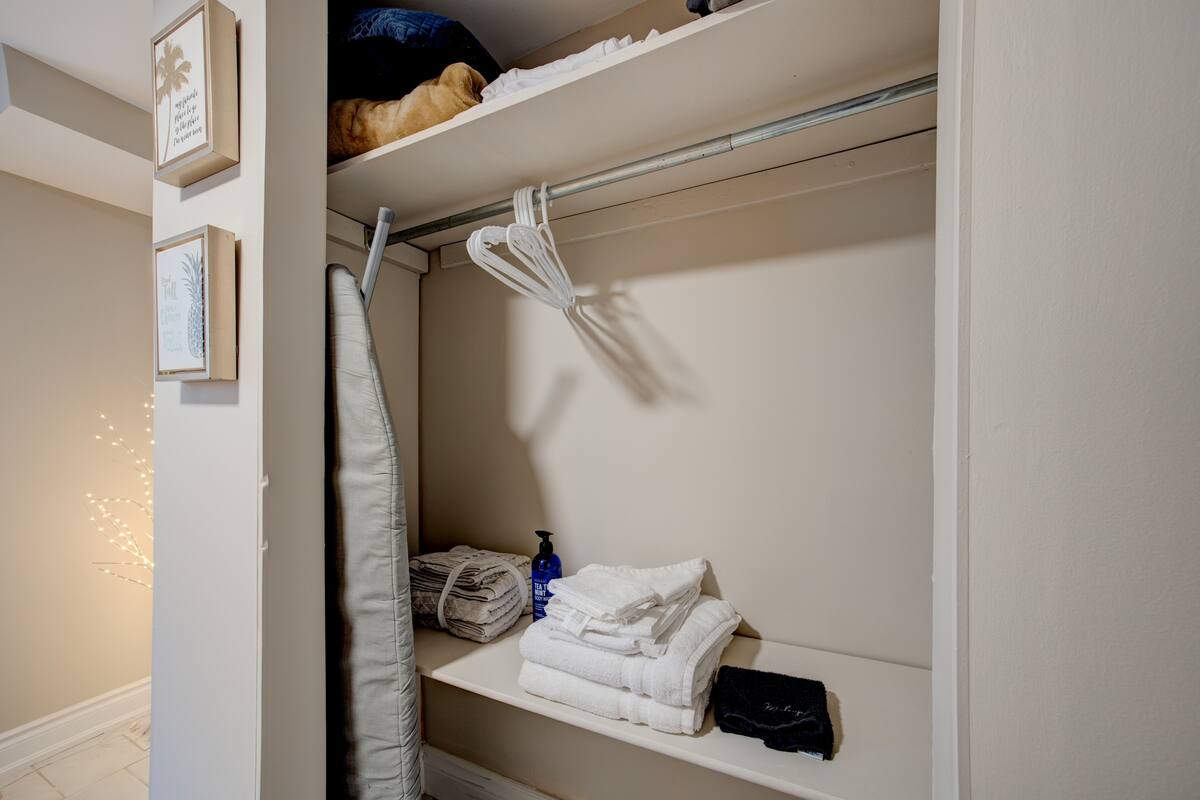Stocked closet with hangers, towels, ironing board & extra bedding.