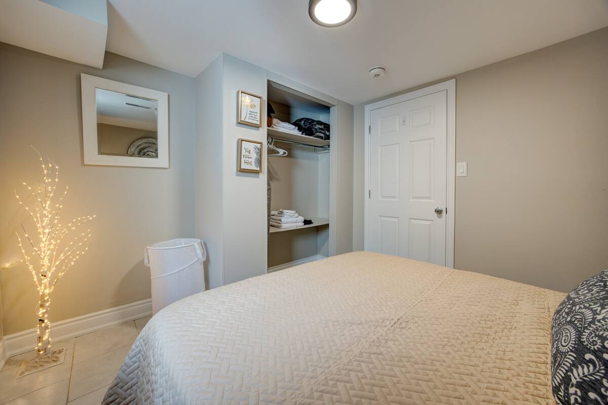 Calm bedroom retreat with open closet, extra linens, and warm lighting