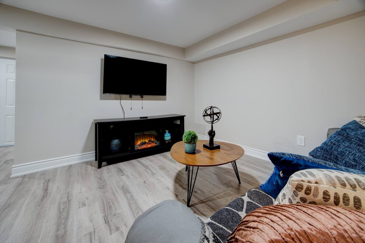 Cozy media room with wall-mounted TV, electric fireplace, plush seating.