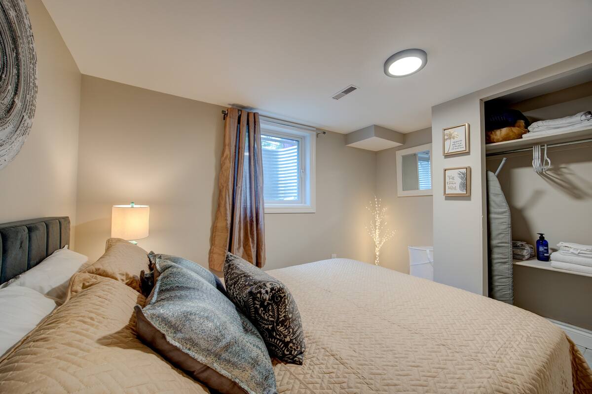 Cozy queen bedroom with open closet, soft lighting, and fresh linens