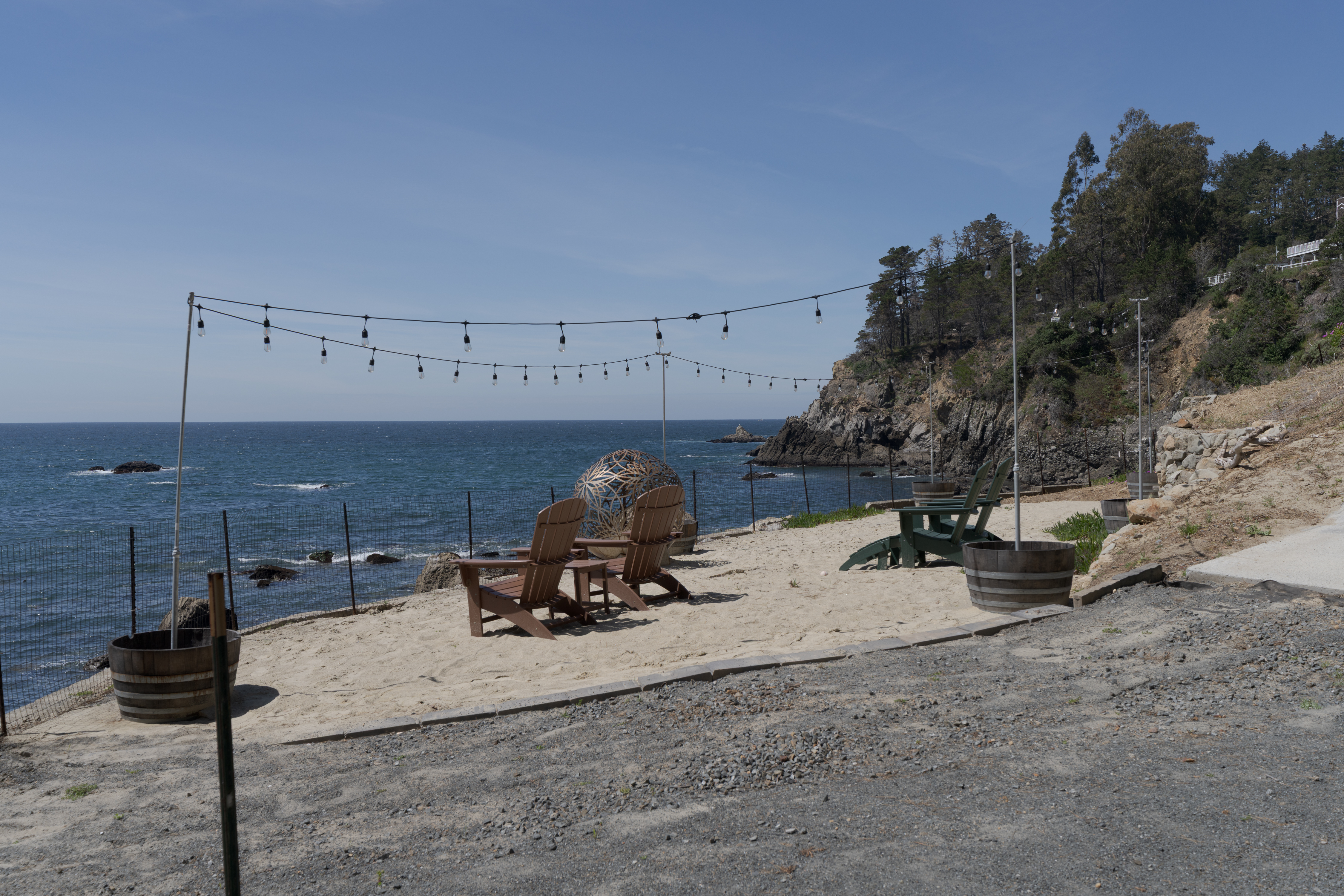 Oceanfront lounge with string lights, Adirondacks & cliffside views.