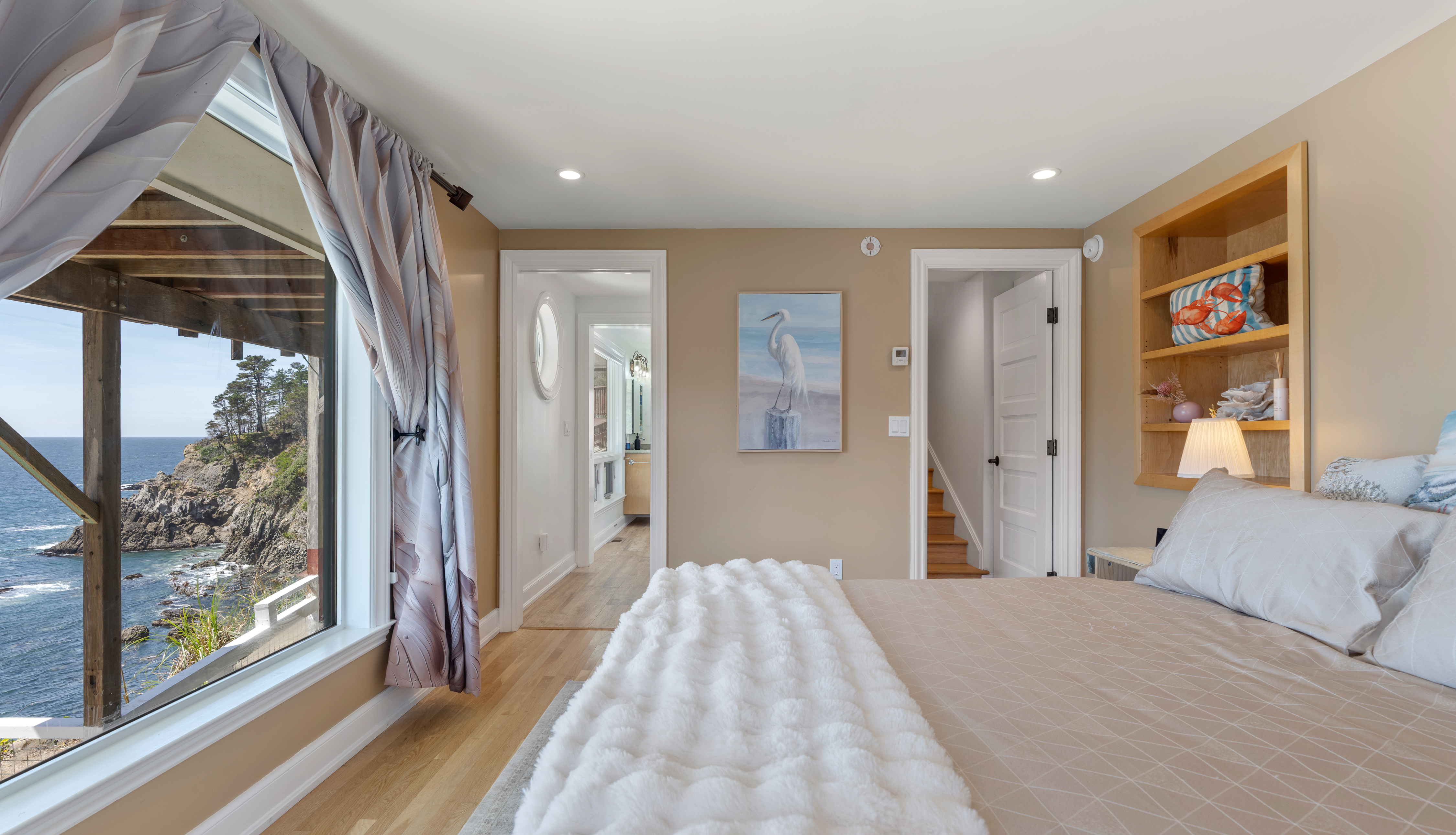 Oceanfront bedroom with cliff views, plush bedding, and en-suite access.