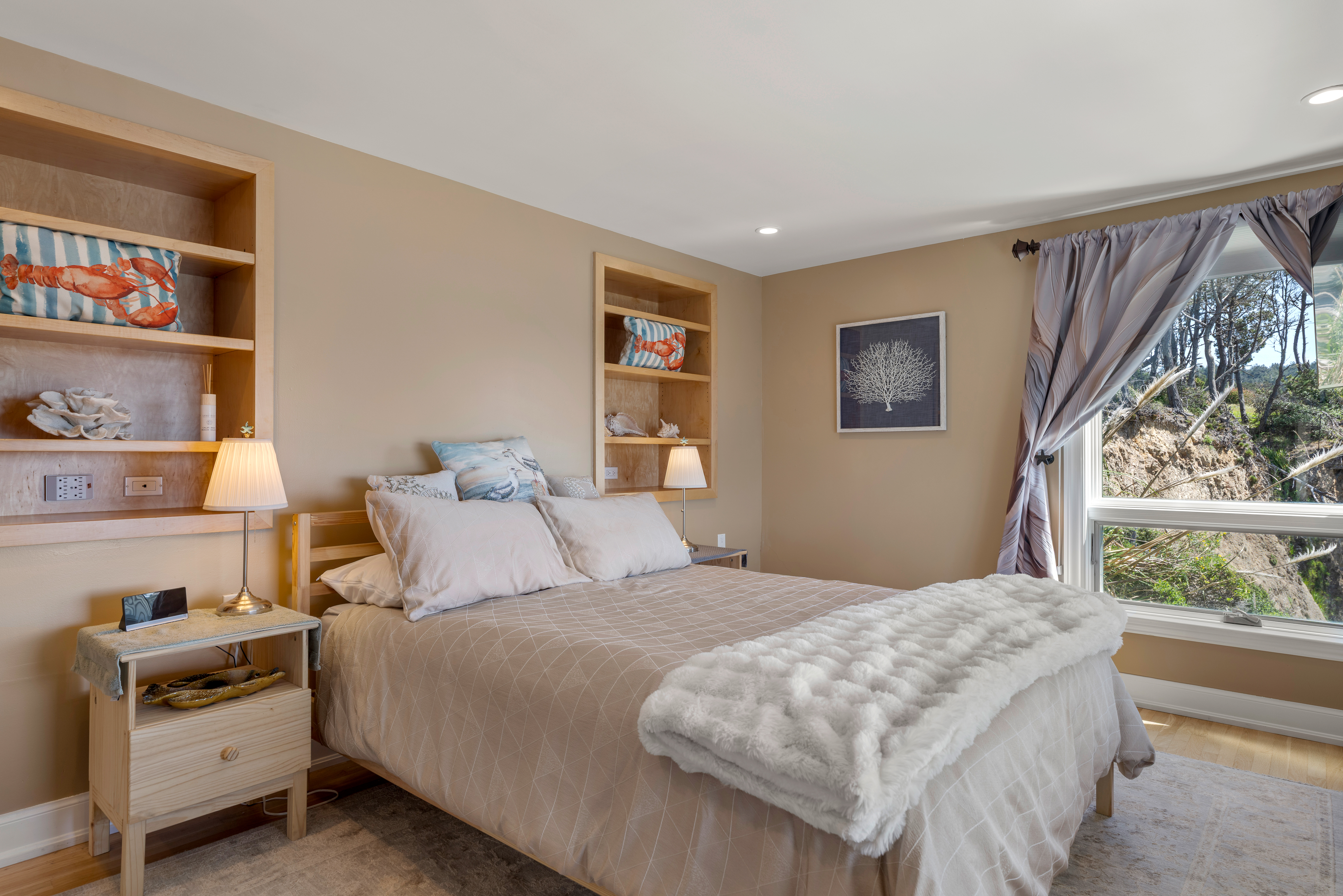 Cozy coastal bedroom with built-ins and sunny window views.