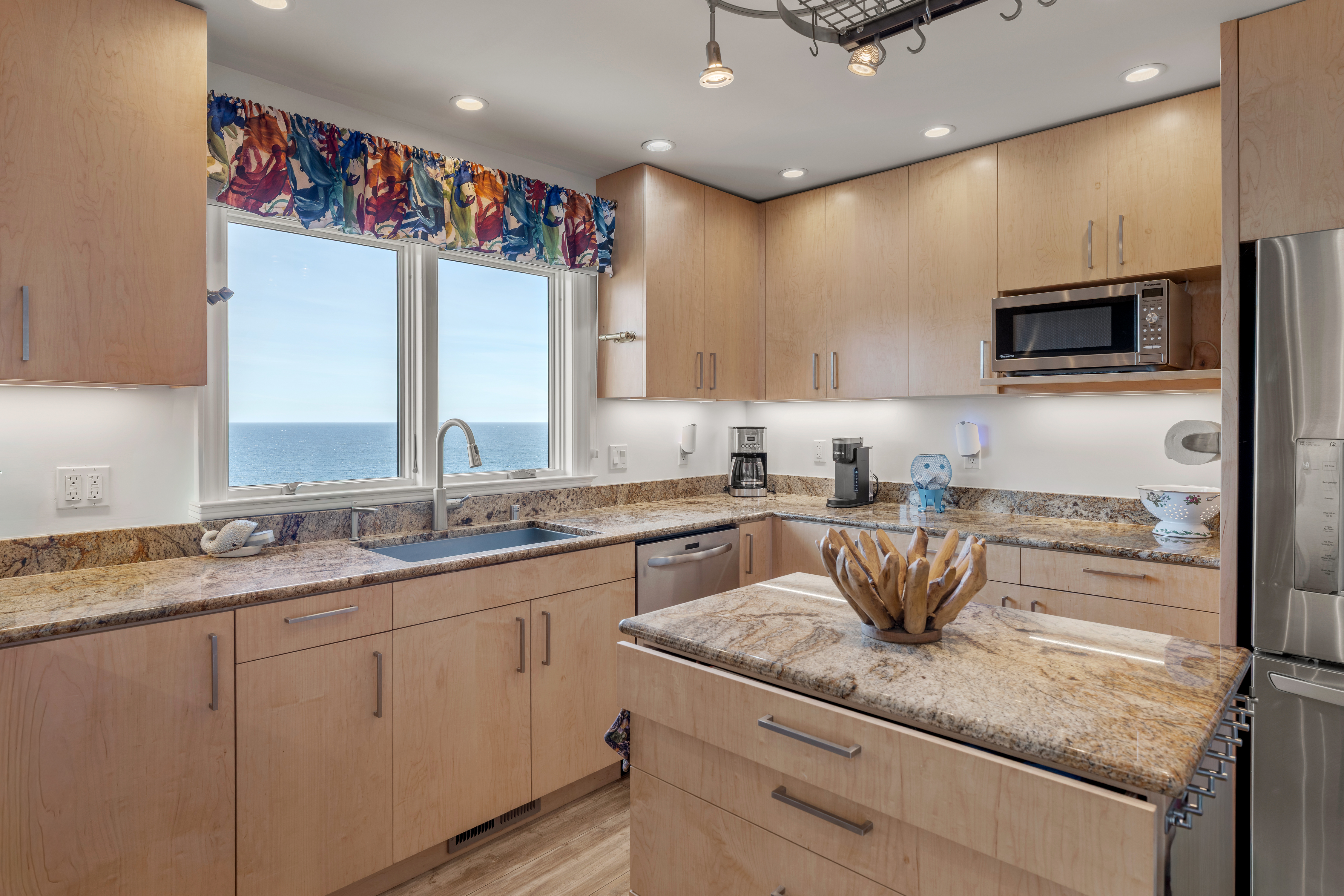 Bright ocean-view kitchen with granite island and stainless appliances