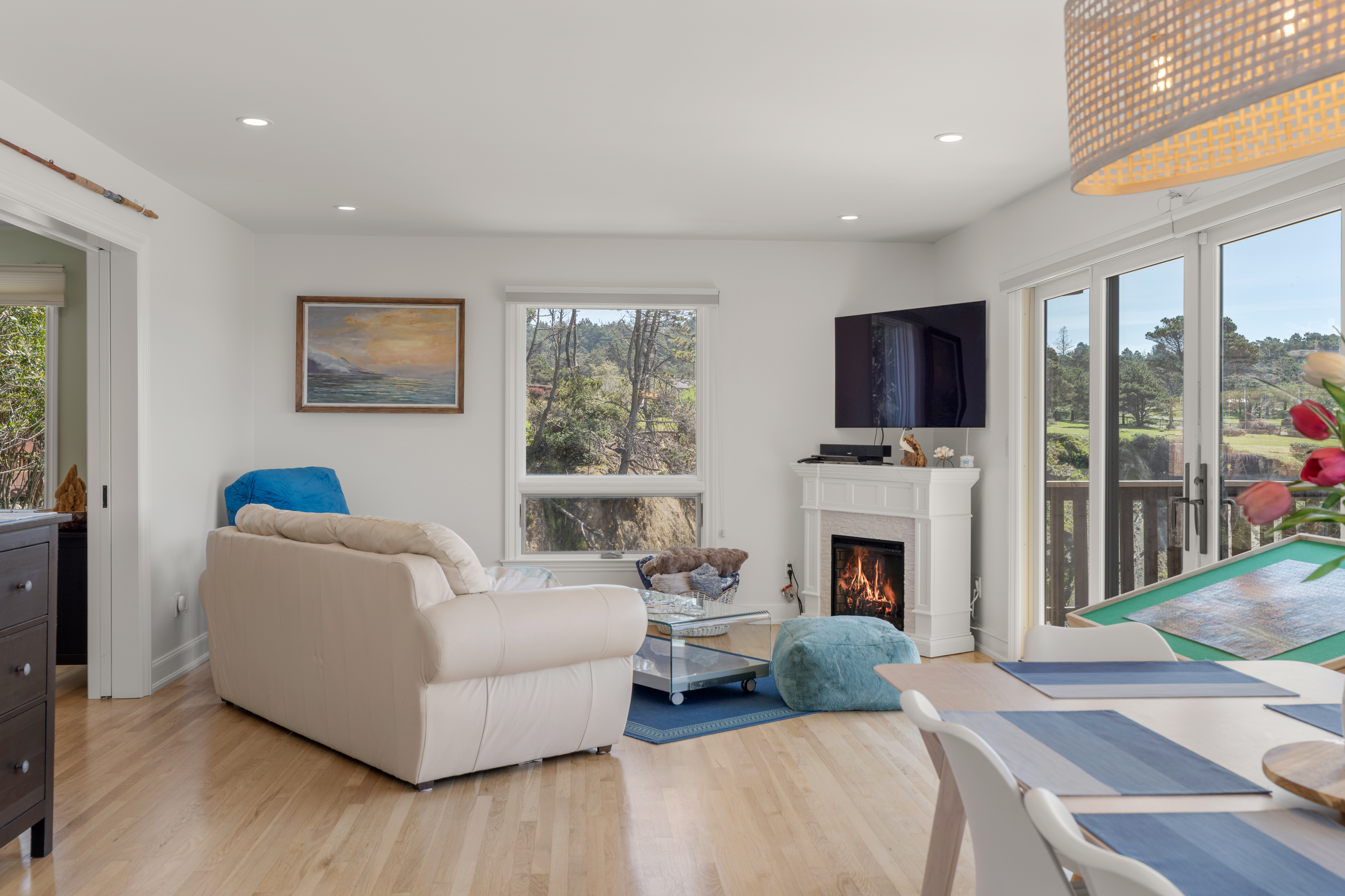 Bright living-dining with fireplace, balcony, and peaceful forest views