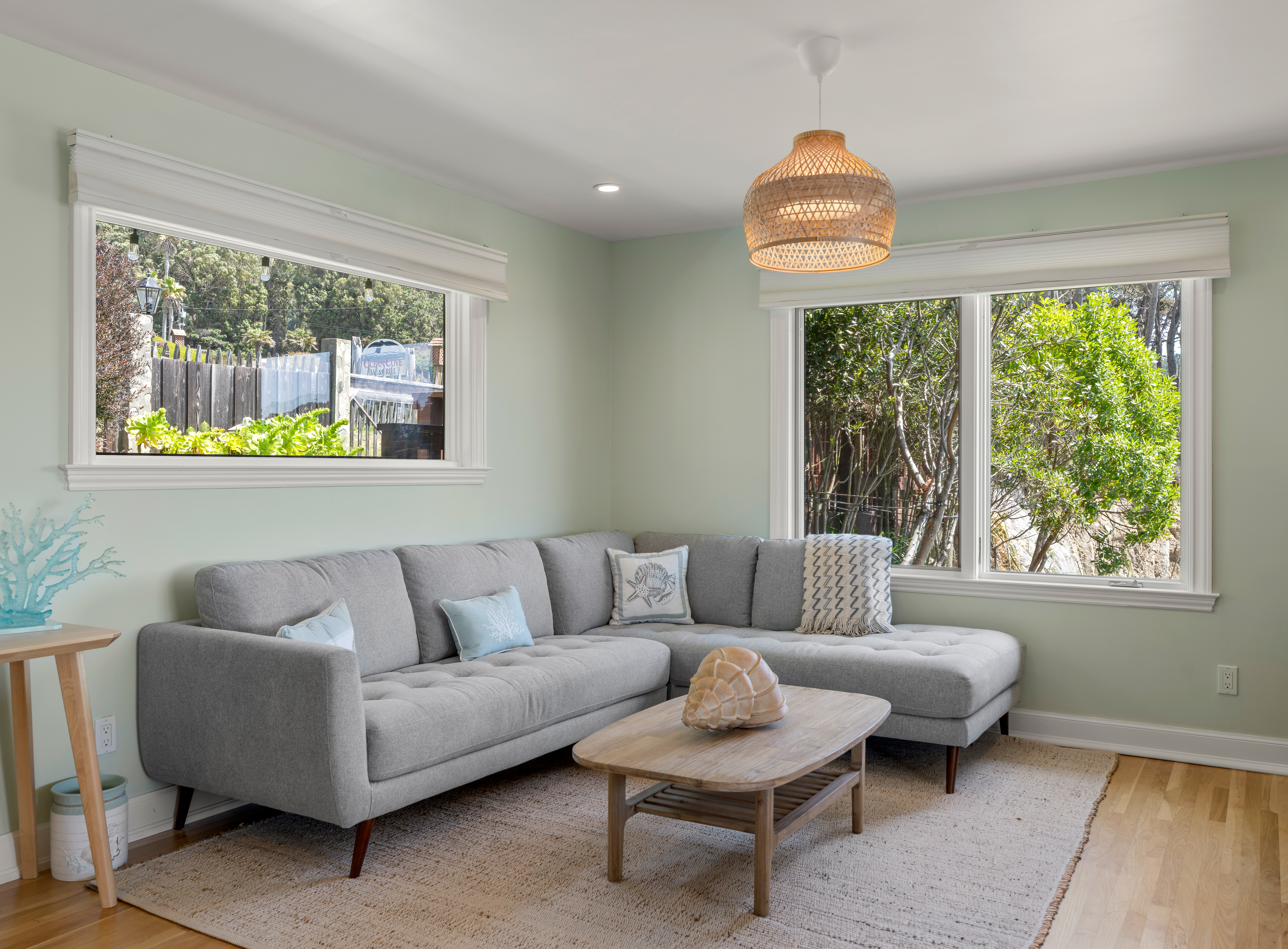 Bright lounge with garden views, cozy sectional, and chic coastal vibes.