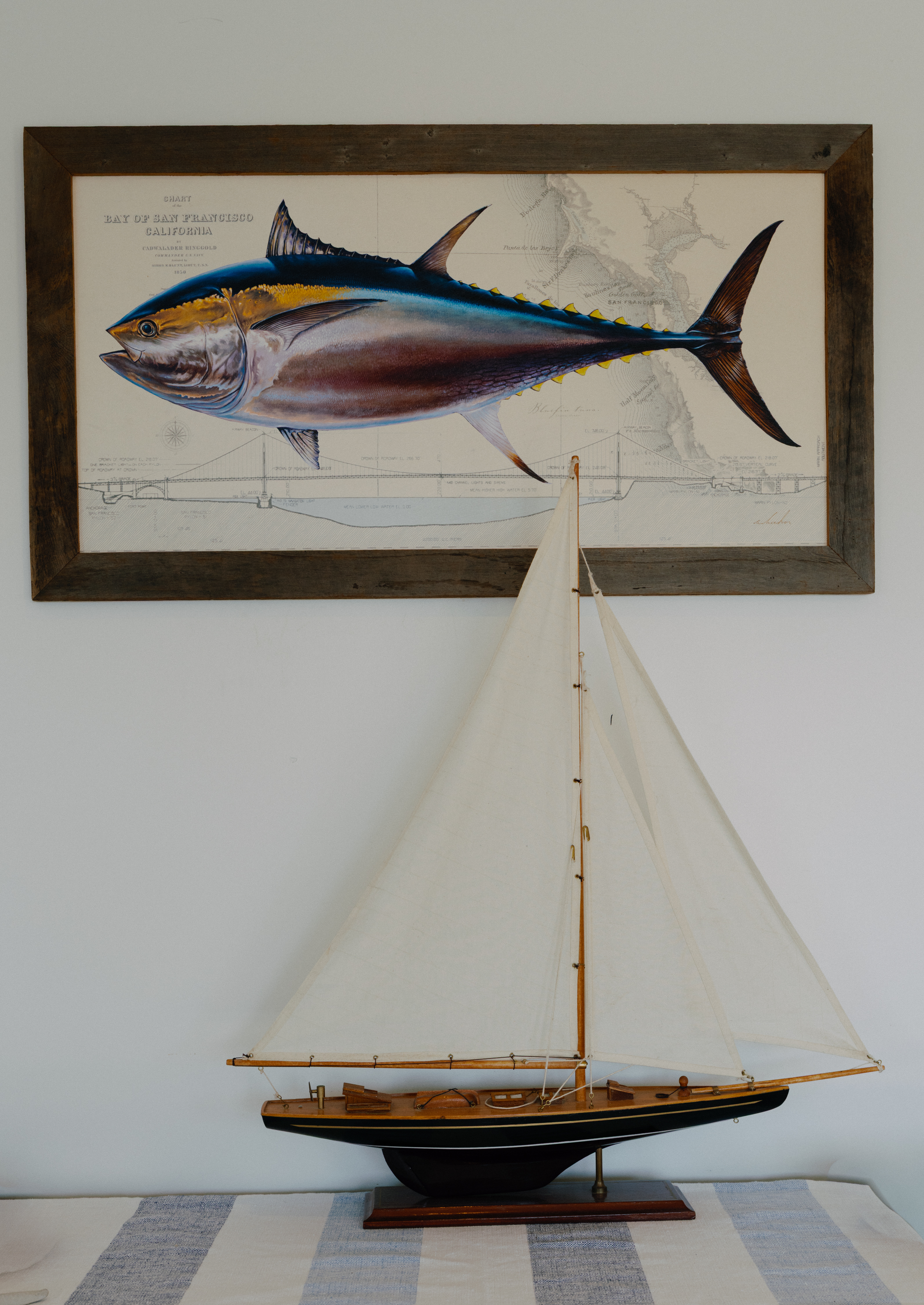 Coastal charm: vintage fish art and a handcrafted sailboat centerpiece