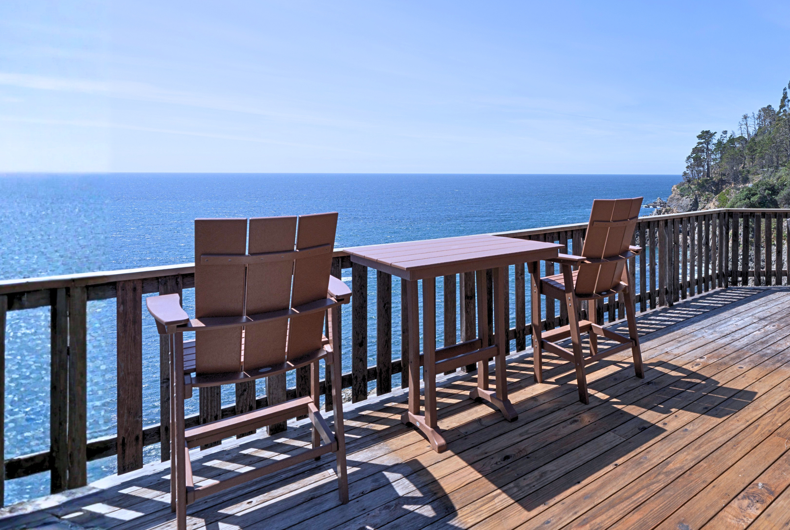 Oceanfront deck with high-top seating and sweeping cliffside views.