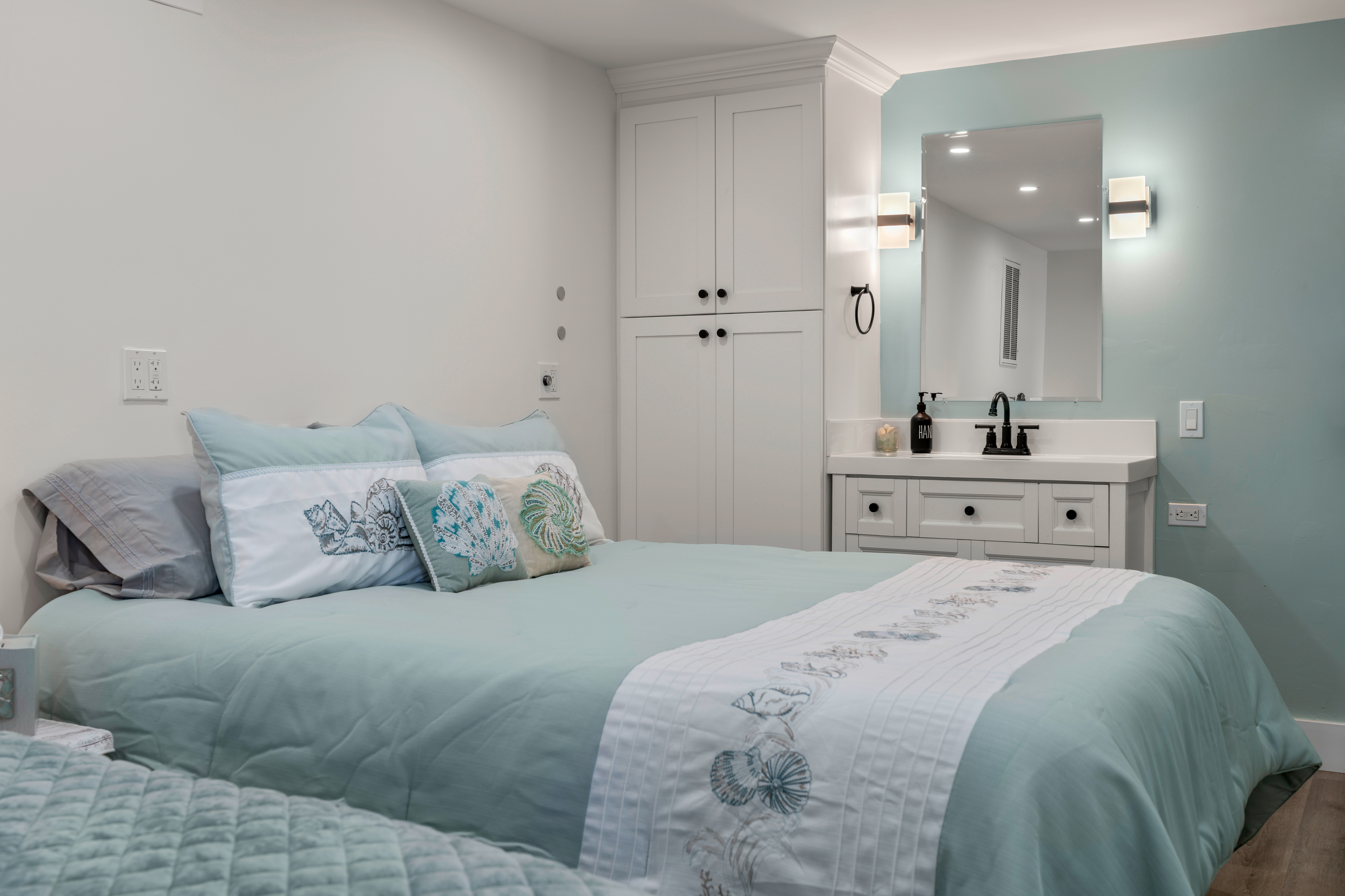 Calming coastal bedroom with built-ins and sleek vanity lighting
