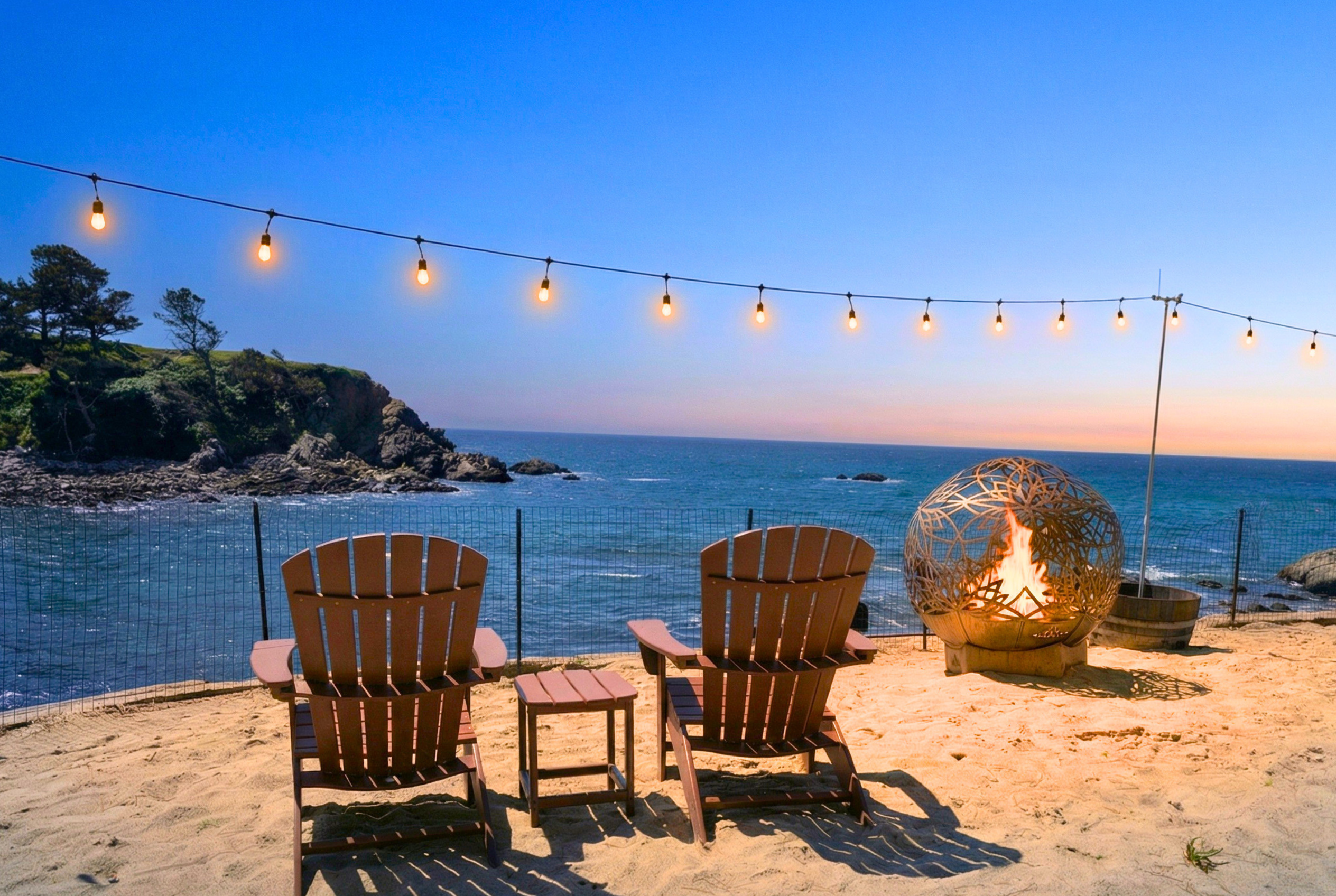 Oceanfront lounge with fire pit, string lights, and breathtaking sunset views