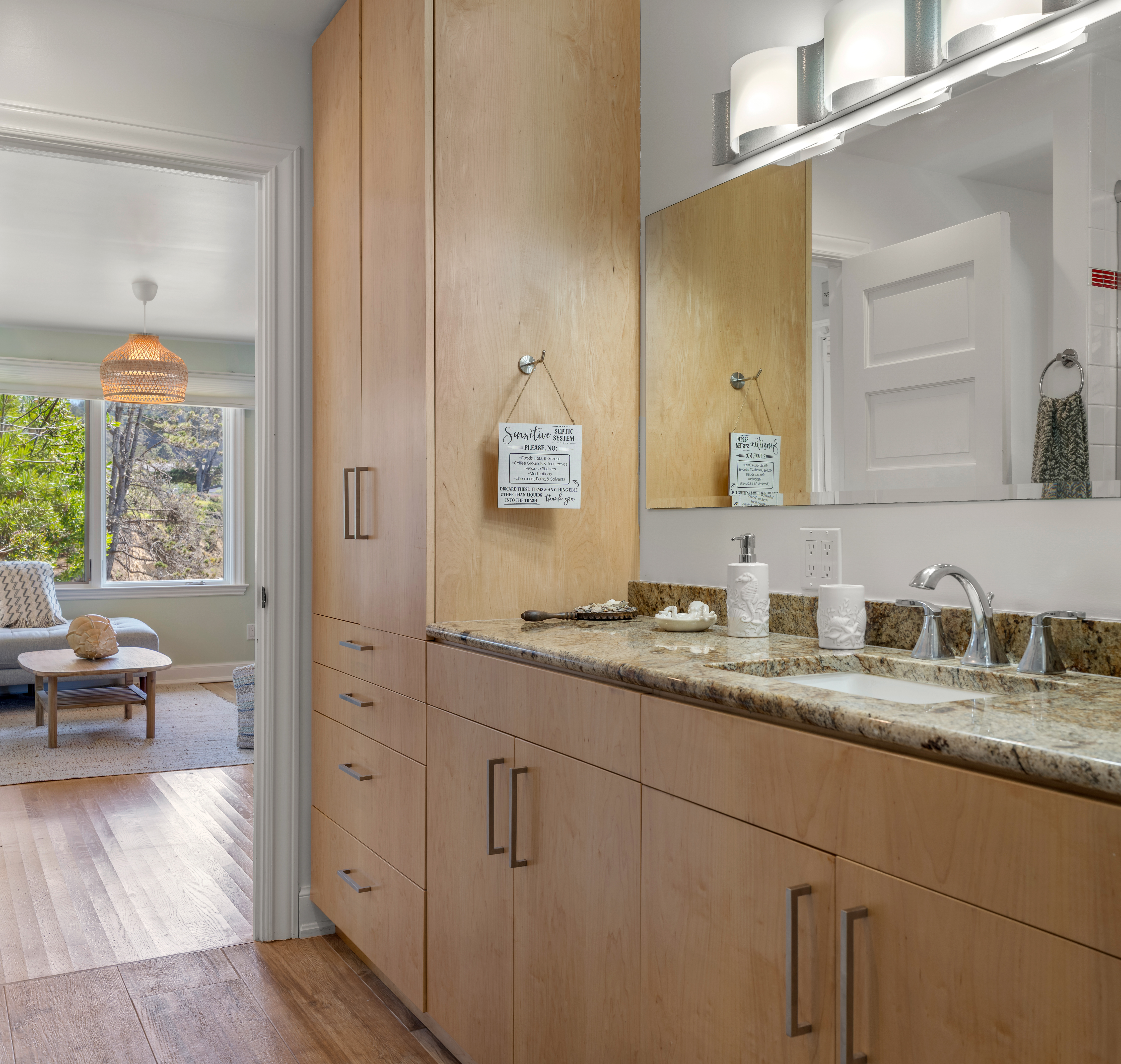 Granite vanity + ample storage, opening to a lounge with treetop views