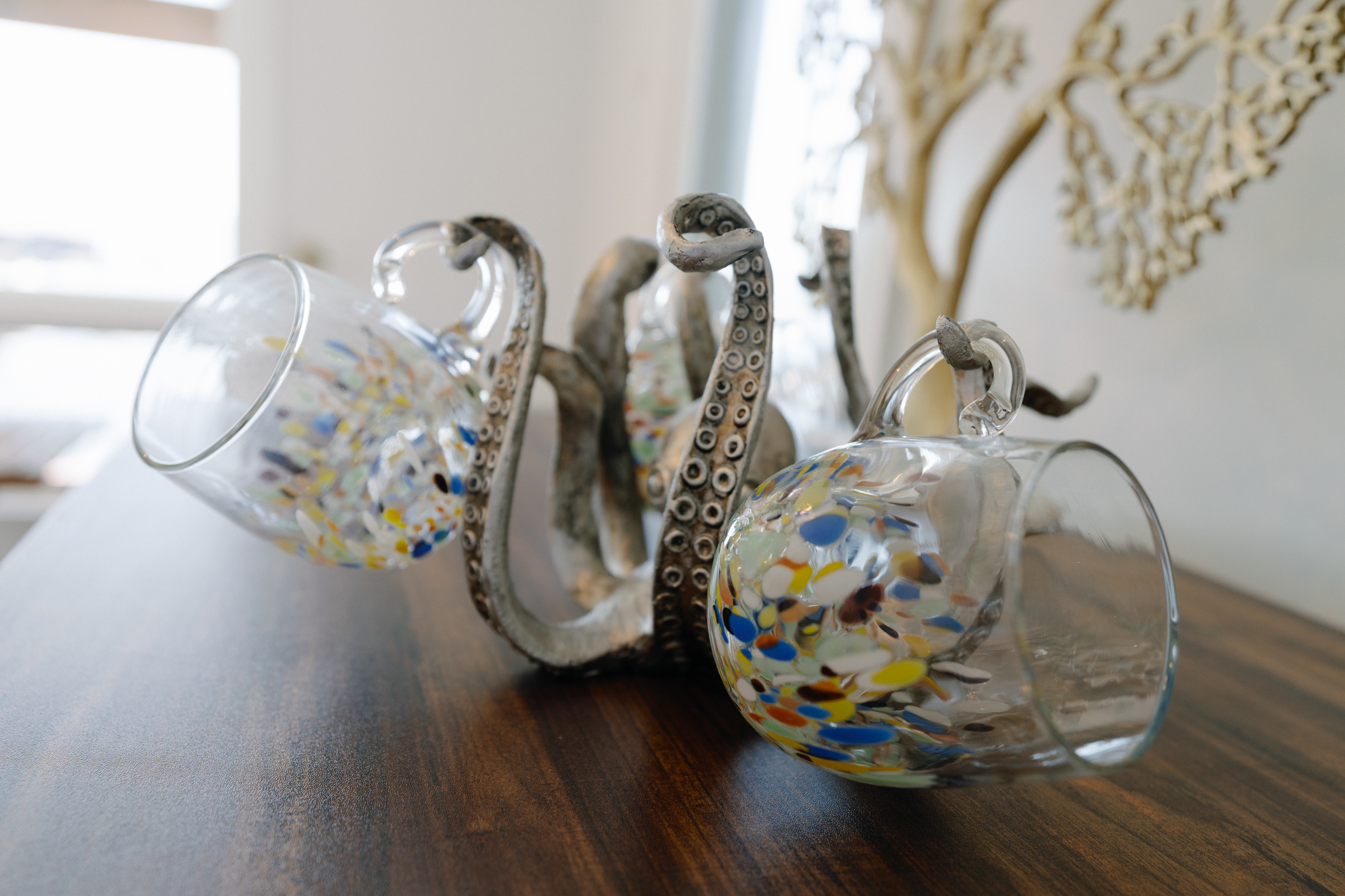Coastal-chic detail: speckled glass mugs on an octopus stand by daylight.