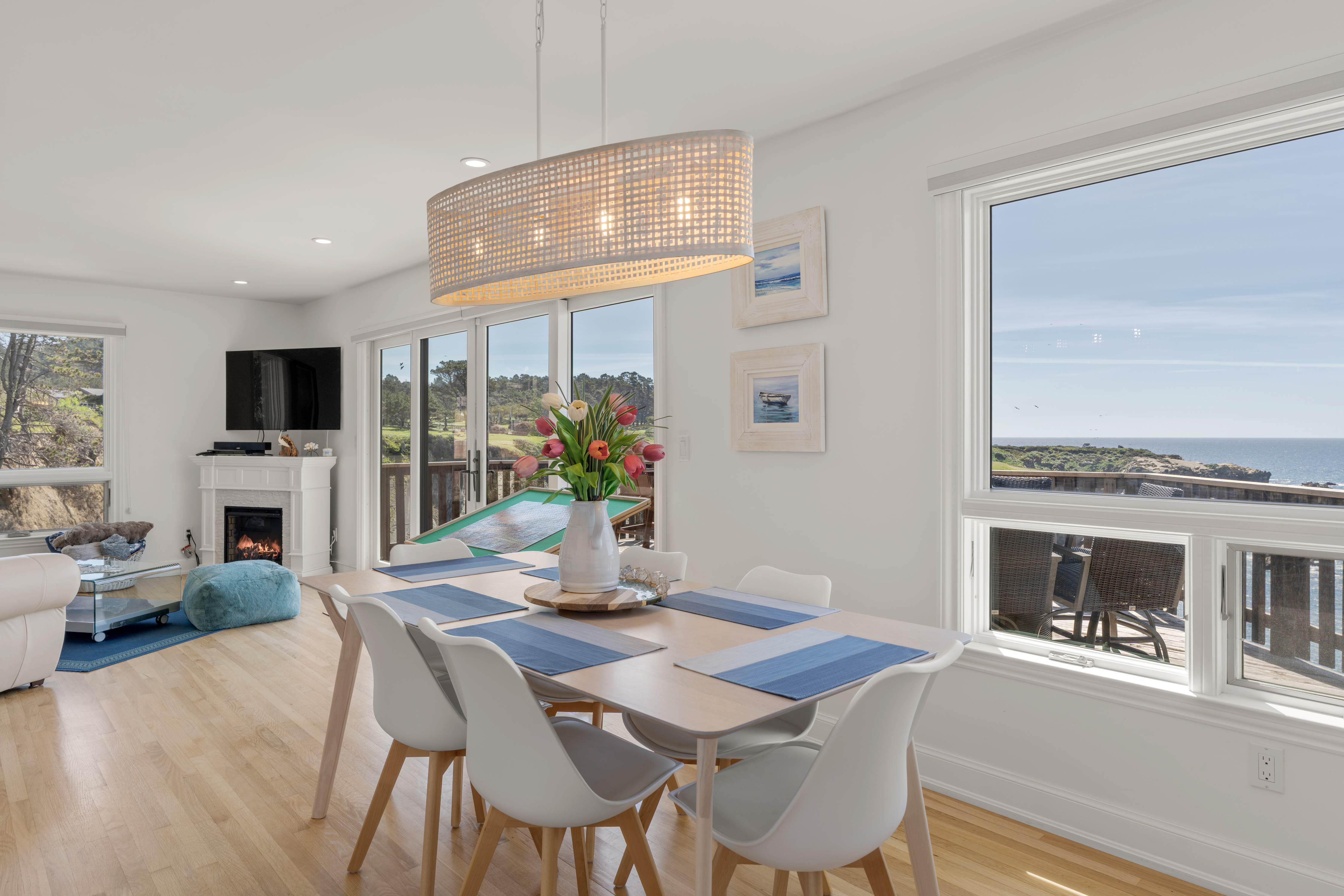 Bright coastal dining-living with ocean views, deck and fireplace.