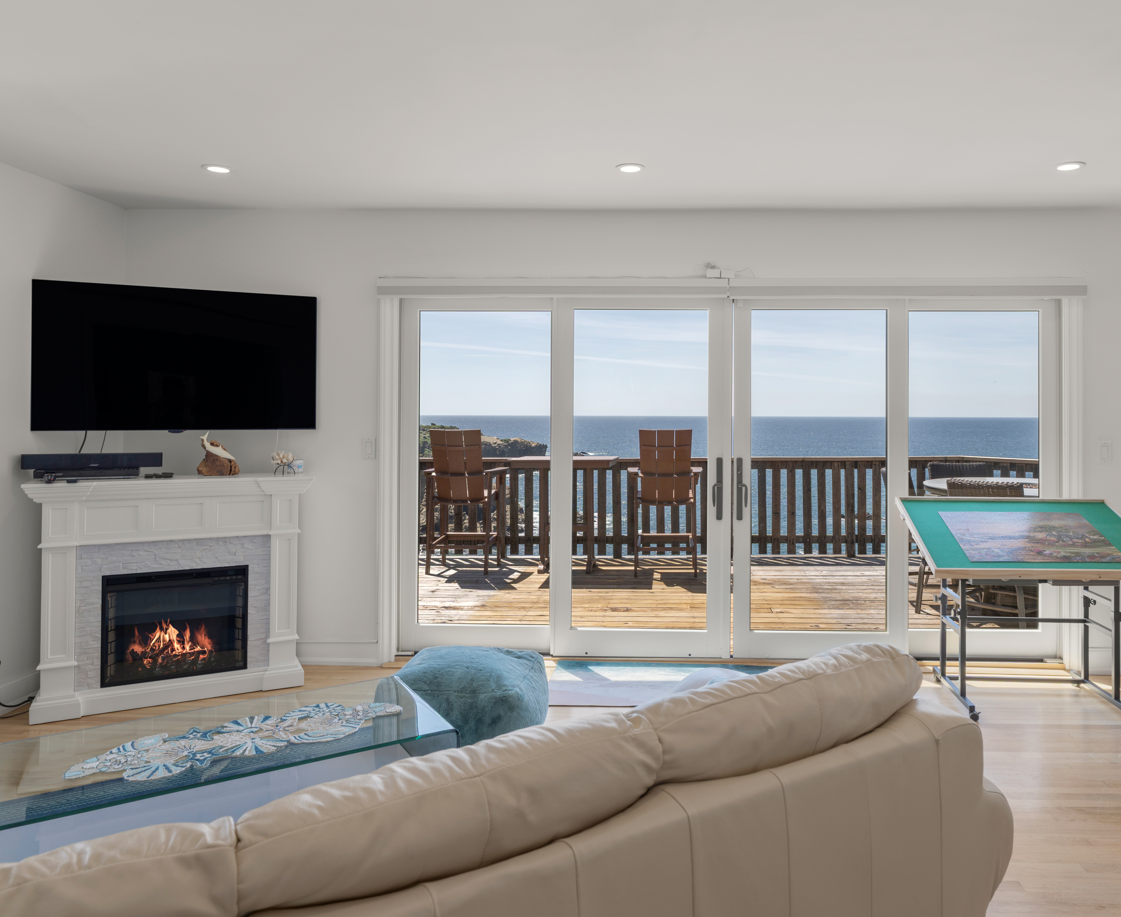Bright living room with oceanfront deck, fireplace, and big views