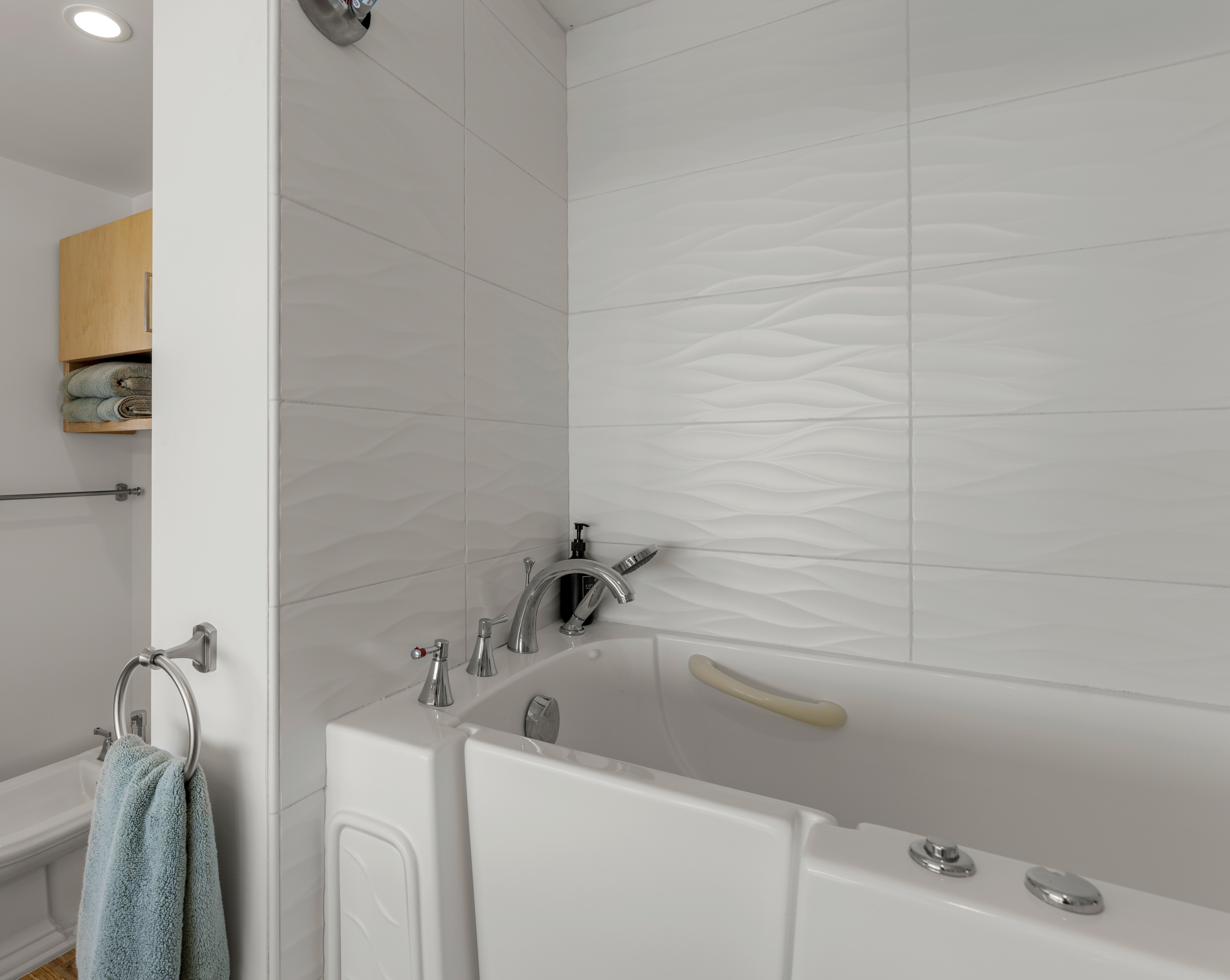 Modern bath with walk-in soaking tub, wave tile, and chrome fixtures