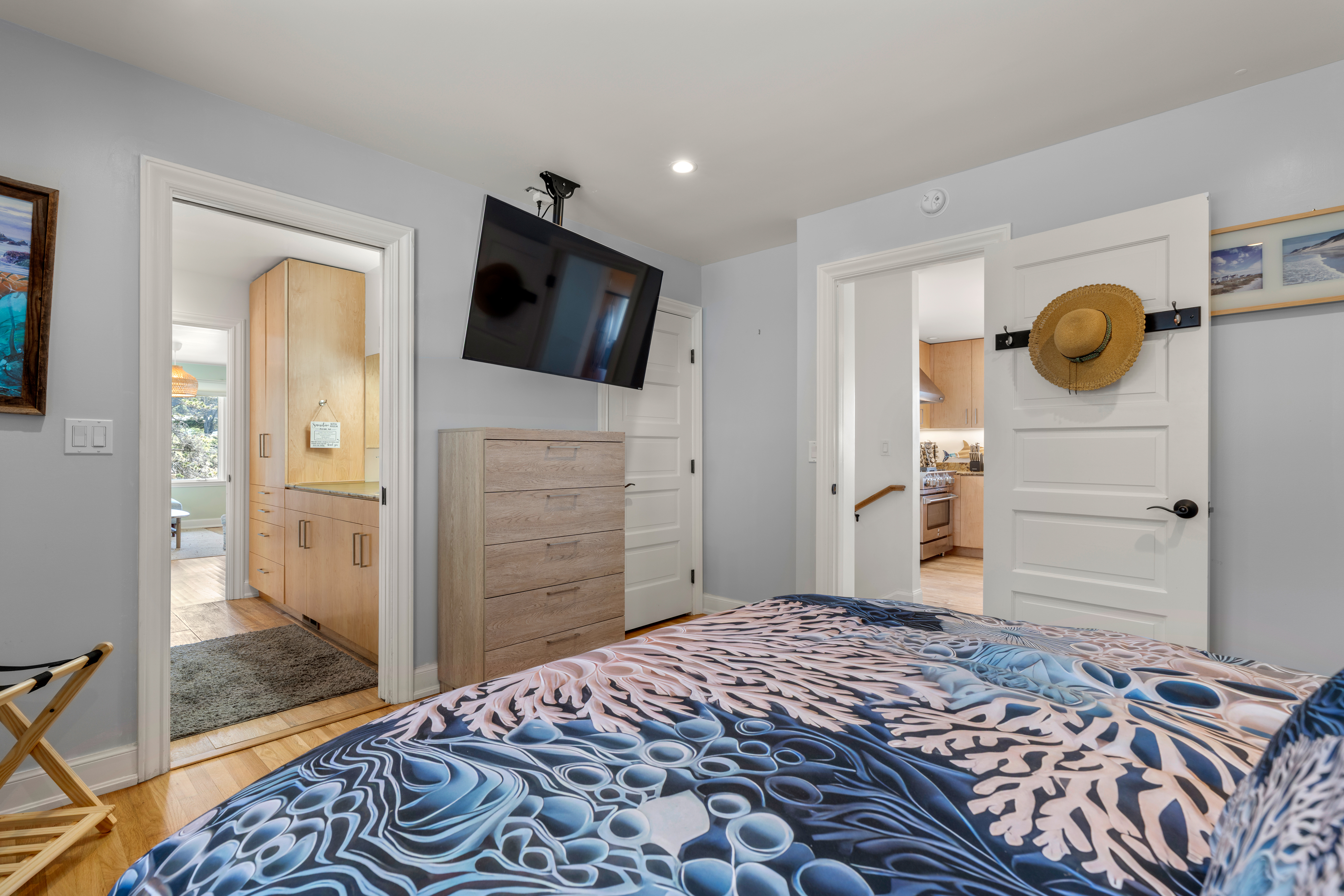 Cozy bedroom with wall‑mounted TV, dresser storage, and bath access.