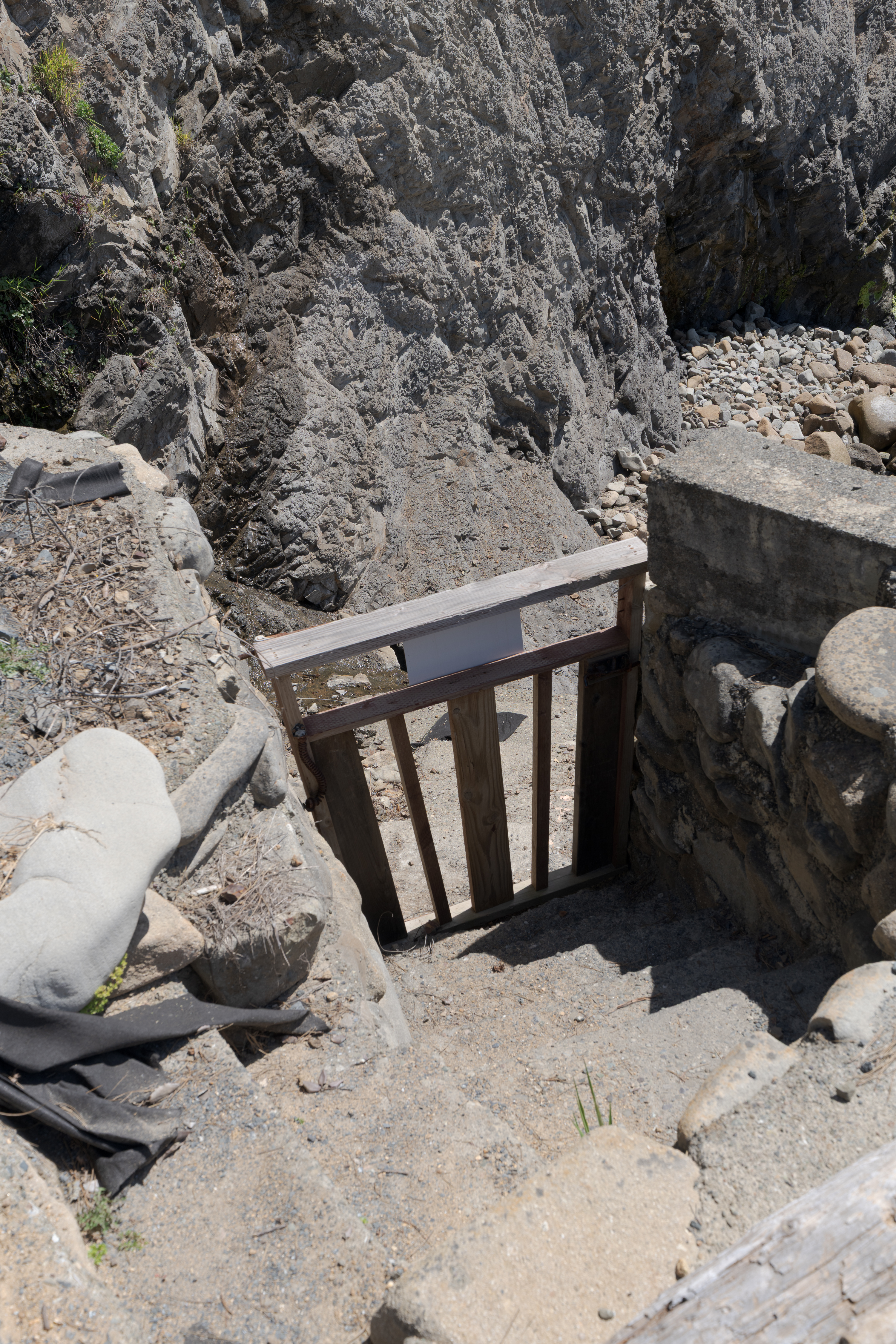 Gated stone steps lead to a secluded rocky beach—dramatic coastal access.