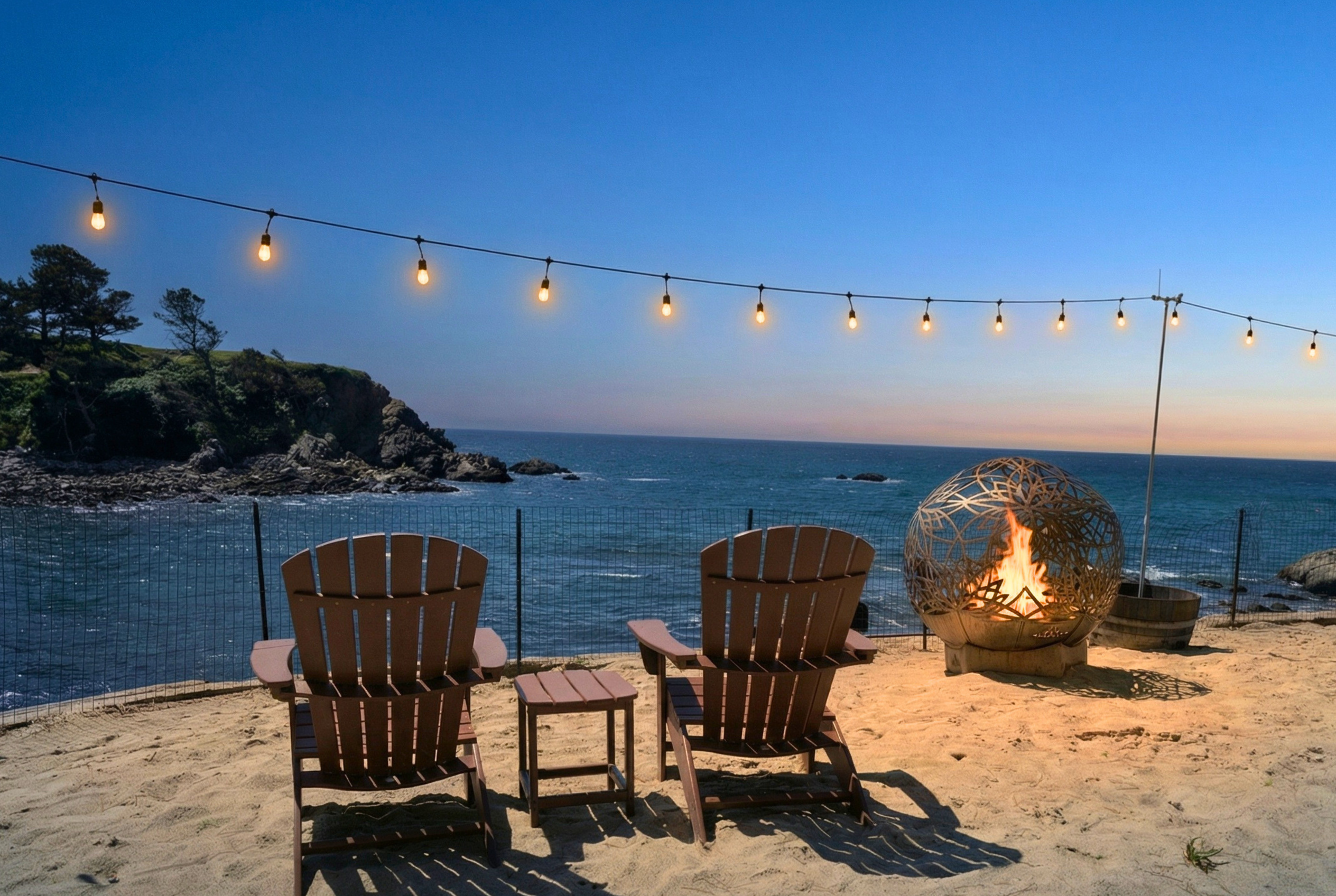 Oceanfront fire pit with Adirondack seating under twinkling lights